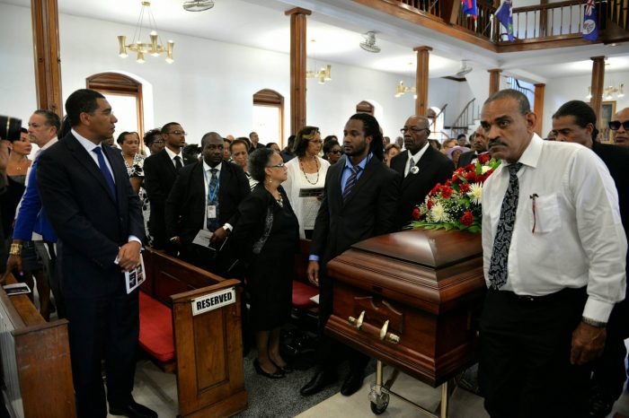 Prime Minister, the Most Hon. Andrew Holness (left), observes as pall-bearers take the casket of the late realist painter Cecil Cooper from the Chapel at the Mona Campus of the University of the West Indies, on September 28, following the Thanksgiving Service.