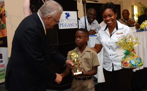 Minister of Industry, Commerce, Agriculture and Fisheries, Hon. Karl Samuda, presents the Ministry’s trophy to Asher Harrison of Greater Portmore Primary School, who was the winner in the primary school category of the Praedial Larceny Prevention Unit (PLPU) inaugural essay competition in 2016. Sharing the moment is Marketing Coordinator at Newport Fersan, Joan Sharpe Colley.