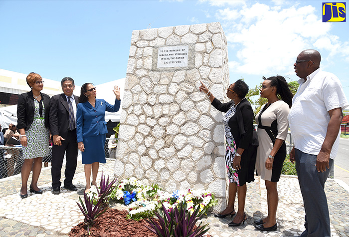 Minister of Culture, Gender, Entertainment and Sport, Hon. Olivia Grange (third right); and Minister of Labour and Social Security, Hon. Shahine Robinson (third left), point to the top of the Workers’ Monument where an image will be erected to honour those persons who fought during the labour movement 80 years ago. Occasion was the annual Commemoration and Remembrance Ceremony at the monument, downown Kingston  on Tuesday (May 15). Looking on (from left) are Chief Financial Officer, Kingston Wharves Limited, Clover Moodie; President, Jamaica Employers’ Federation, David Wan; Vice President, Jamaica Confederation of Trade Unions, Lorraine Brown; and Councillor, Tivoli Gardens Division, Donovan Samuels.    