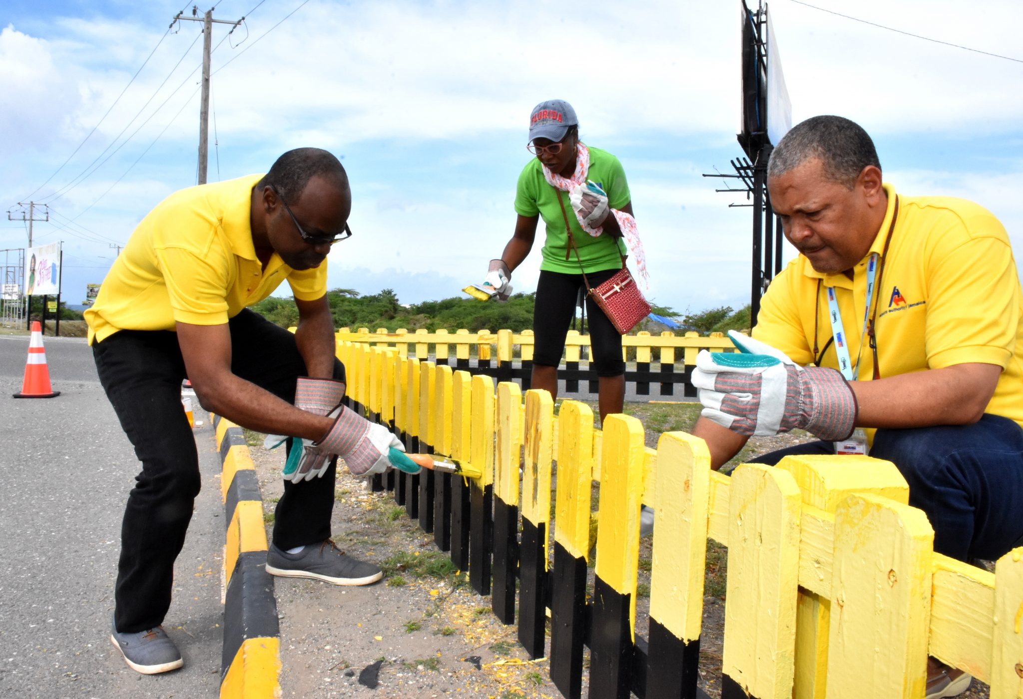 President and Chief Executive Officer (CEO) of the Airports Authority of Jamaica (AAJ), Audley Diedrick (right) paints a picket fence near the Harbour View roundabout in East Kingston today (May 23). Also painting (from left) are Senior Director, Commercial Development and Planning, Alfred McDonald; and AAJ General Counsel, Verona Vacianna.