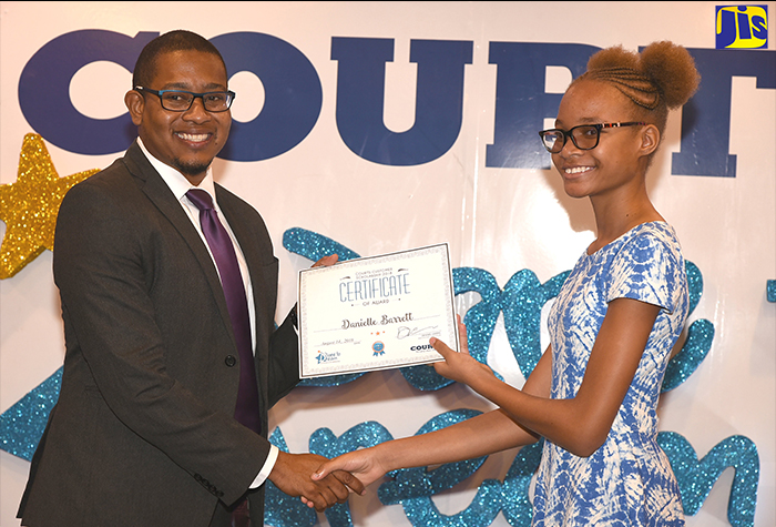 Minister of State in the Ministry of Education, Youth and Information Minister, Hon. Floyd Green (left), presents a certificate of award to Danielle Barrett at Courts