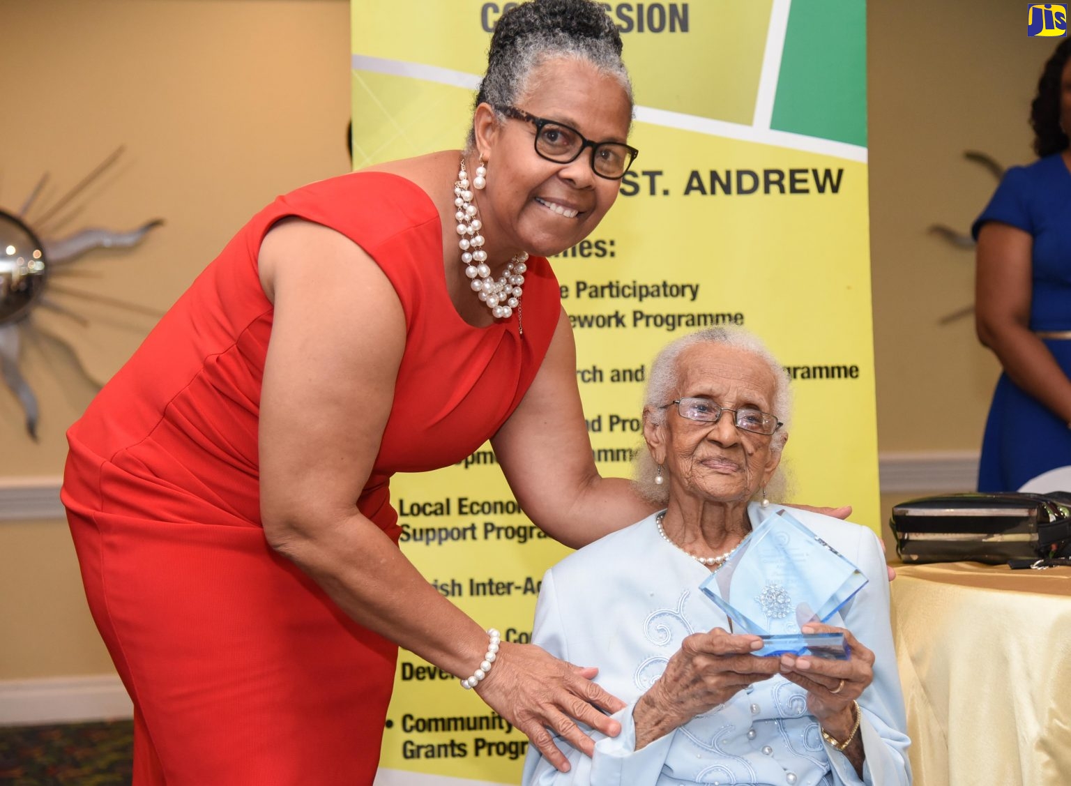 Community development stalwart and centenarian, Hazel Espeut (seated), is presented with the Kingston and St. Andrew Leadership and Community Development Award by Social Development Commission (SDC) Kingston and St. Andrew Parish Manager, Sandra Goulbourne. Occasion was the SDC's annual Community Incentives and Grants Programme Awards Ceremony at The Knutsford Court Hotel, New Kingston on November 17.