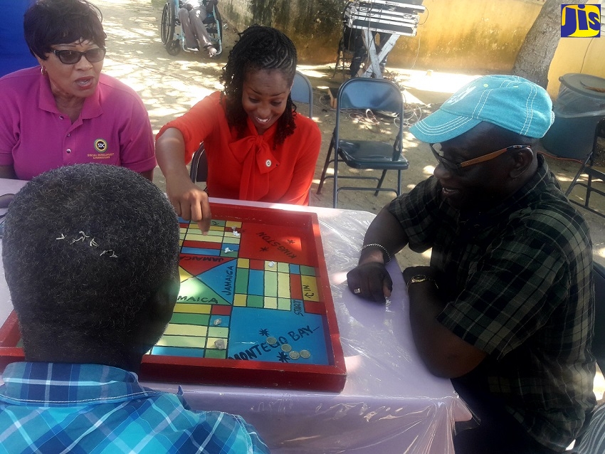 Minister of Local Government and Community Development, Hon. Desmond McKenzie (right), plays ludo with a Hanover Infirmary resident (foreground); Social Development Commission (SDC) Facilitator for Hanover , Cleopatra Kerr (left); and SDC Community Relations Officer for the parish, Alecia Atkinson. The occasion was a day of activities at the infirmary on Wednesday (November 14), in observance of Local Government and Community Development Month, being observed throughout November.