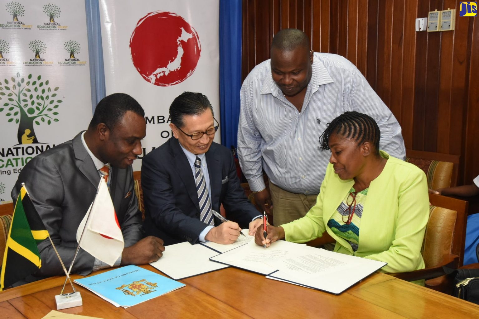 Permanent Secretary in the Ministry of Education, Youth and Information, Dean-Roy Bernard (left), observes as Ambassador of Japan to Jamaica, His Excellency Hiromasa Yamazaki (centre); and Principal of Lyssons Primary School, Evette Bonfield Beecher, sign a grant contract in the amount of US$67,177 (J$8 million) for the purchase of a bus, today (January 22) at the Ministry’s Heroes Circle offices, in Kingston. The grant is being offered through the Government of Japan Grassroots Human Security Project.  Standing is Board Chairman of the school, Cordinal Beckford.