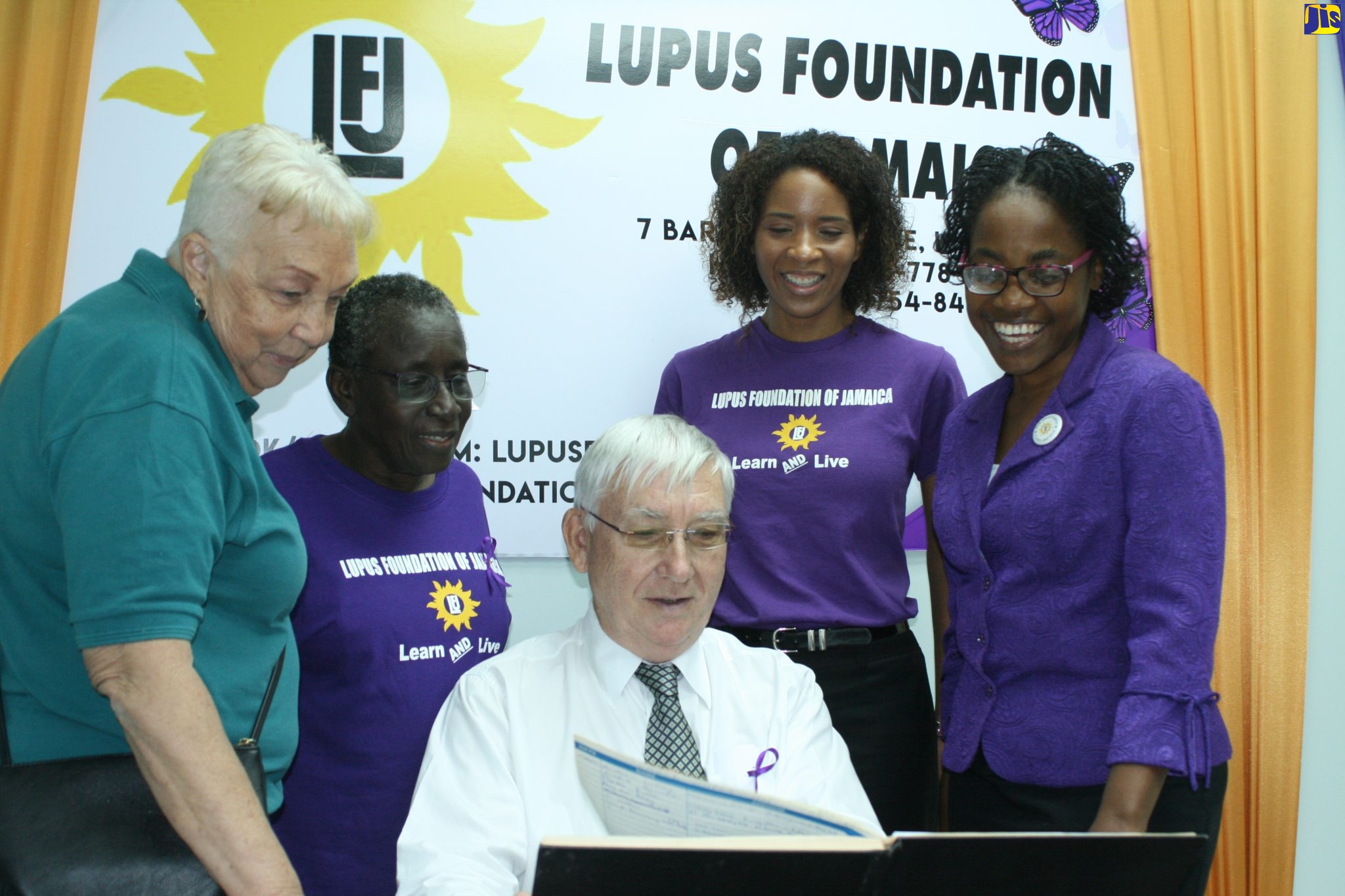 Consultant Rheumatologist at the University Hospital of the West Indies (UHWI), Dr. Karel DeCeulaer (seated), looks through a report during a World Lupus Day event held recently, at the Lupus Foundation of Jamaica (LFJ) in New Kingston. Others looking on (from left) are group members Rosemary Nethersole, and Rev. Verna Cassells; President of the Foundation, Dr.  Desirée Tulloch-Reid; and member of the group and lupus patient, Chrisendeen Douglas.