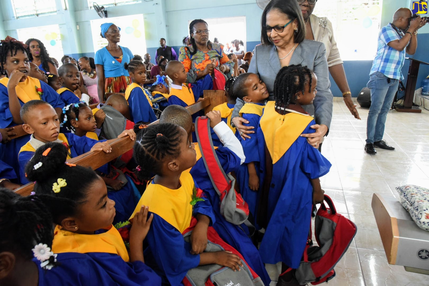 Minister of Labour and Social Security, Hon. Shahine Robinson (right), interacts with students at the Early Stimulation Programme (ESP) transitional exercise, held at the Apostolic Church of Jamaica Bethel Temple, Kingston Gardens, on July 10. The ESP is an early intervention programme for young children (0-6 years) with various types of developmental disabilities. A total of 60 students graduated from the ESP, 50 of whom will be matriculating to primary special education and 10 students to the regular school system.