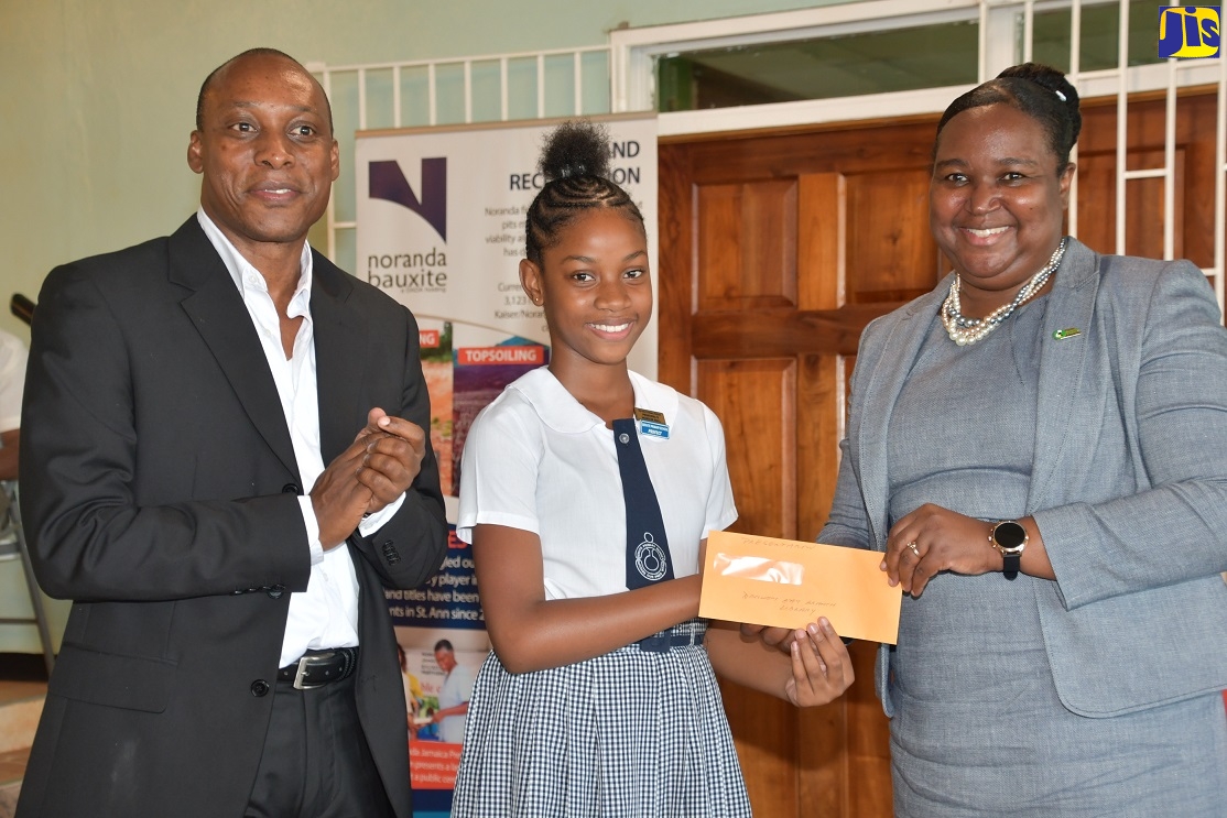 Acting Permanent Secretary in the Ministry of Education, Youth and Information, Dr. Grace McLean (right), makes a presentation to Abrianna Greaves (centre) from Servite Primary in Brown’s Town, St. Ann, who was named the top performing girl at the Noranda Jamaica Bauxite Partners' Primary Exit Profile (PEP) awards ceremony at the Port Rhoades Sports Club, Discovery Bay, St. Ann, on Thursday, August 15. Sharing in the moment is Vice President and General Manager at the company, Delroy Dell. 