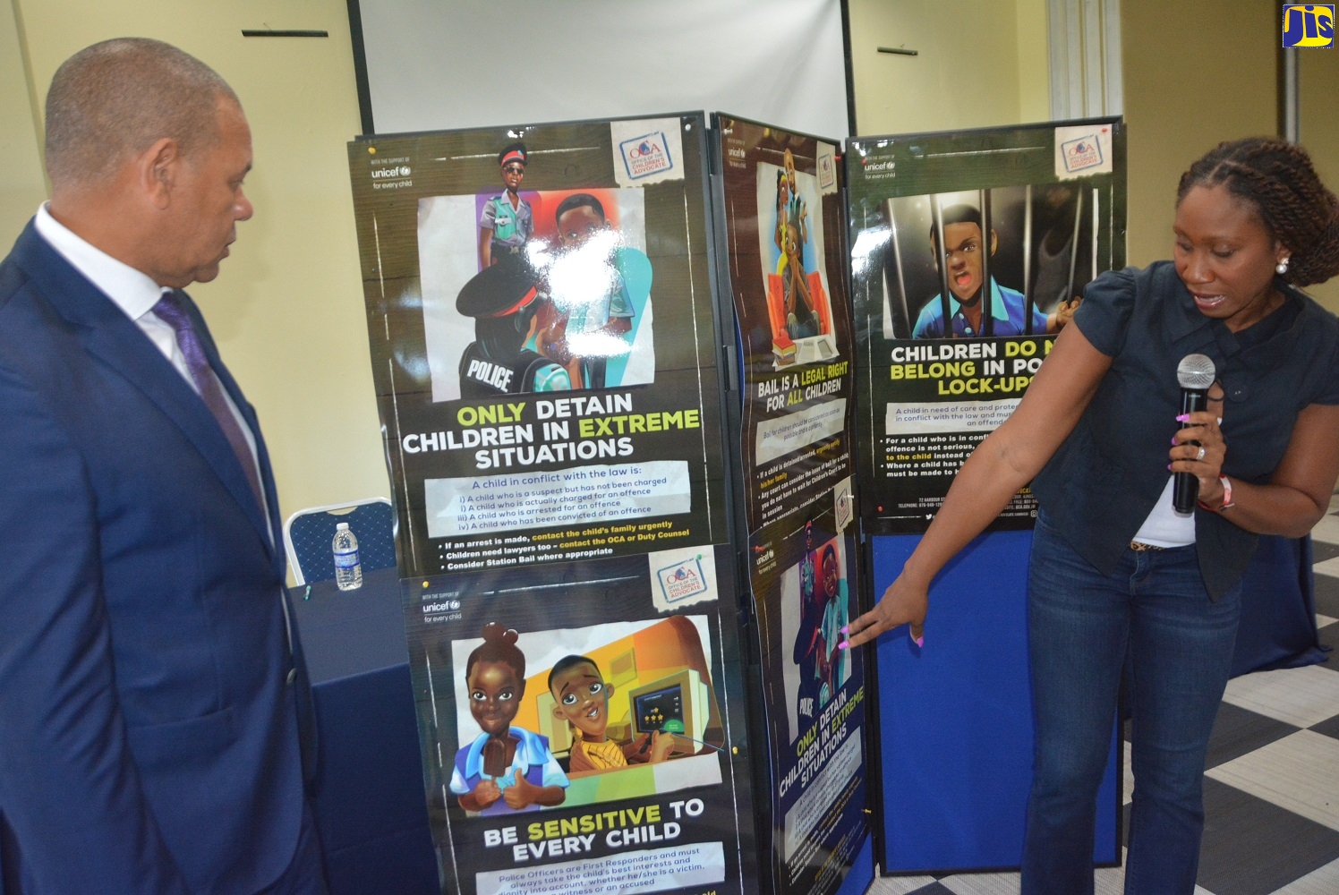 Children’s Advocate, Diahann Gordon Harrison (right), highlights aspects of the Child Justice Guidelines Posters to Deputy Commissioner of Police Clifford Blake, following their launch during the opening ceremony for the Office of the Children’s Advocate’s (OCA) ‘Child Justice Guidelines Training Seminar’ at the Grand Palladium Jamaica Resort and Spa in Hanover on Saturday, September 21.