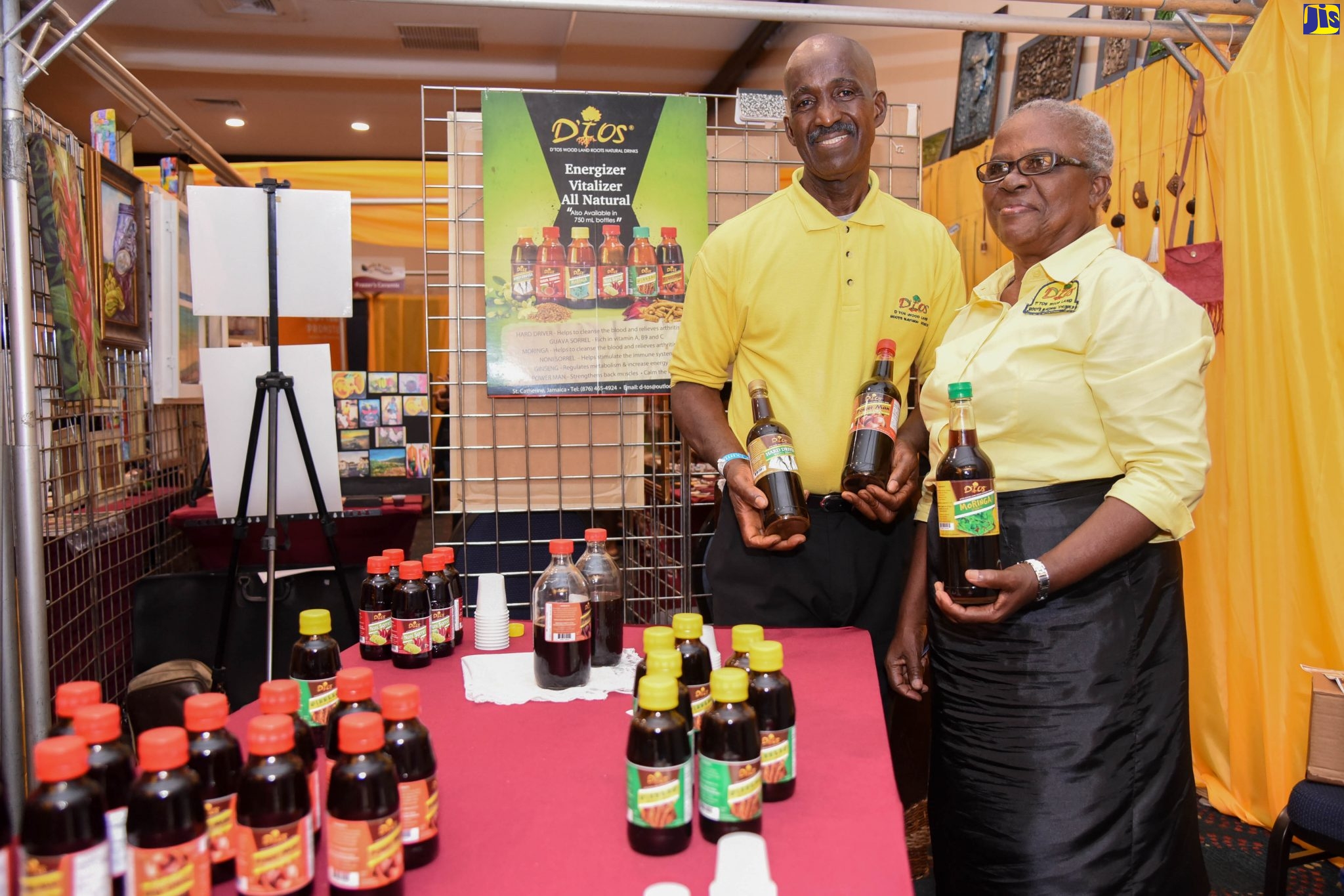 Chief Executive Officer, Wood Land Roots Natural Drinks, Oliver Welsh (left), and one of his assistants, Kathleen Brown, display some of his products at the recent Jamaica Business Development Corporation (JBDC) Expo 2019, held at The Jamaica Pegasus hotel in New Kingston.    
