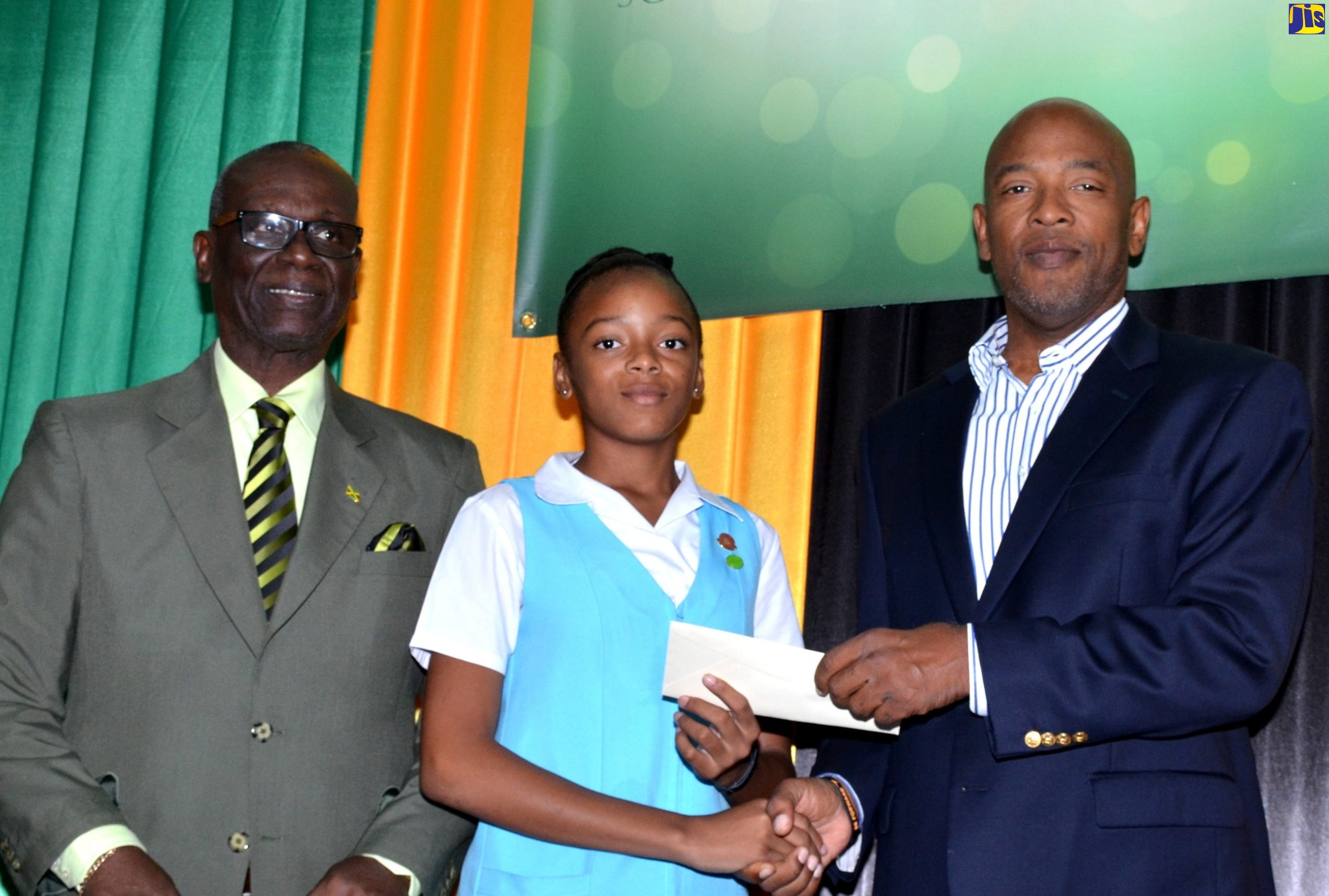 Minister of Local Government and Community Development, Hon. Desmond McKenzie (left), looks on as Christopher Seaga, son of late former Prime Minister, the Most. Hon Edward Seaga, presents a scholarship award to Wolmer