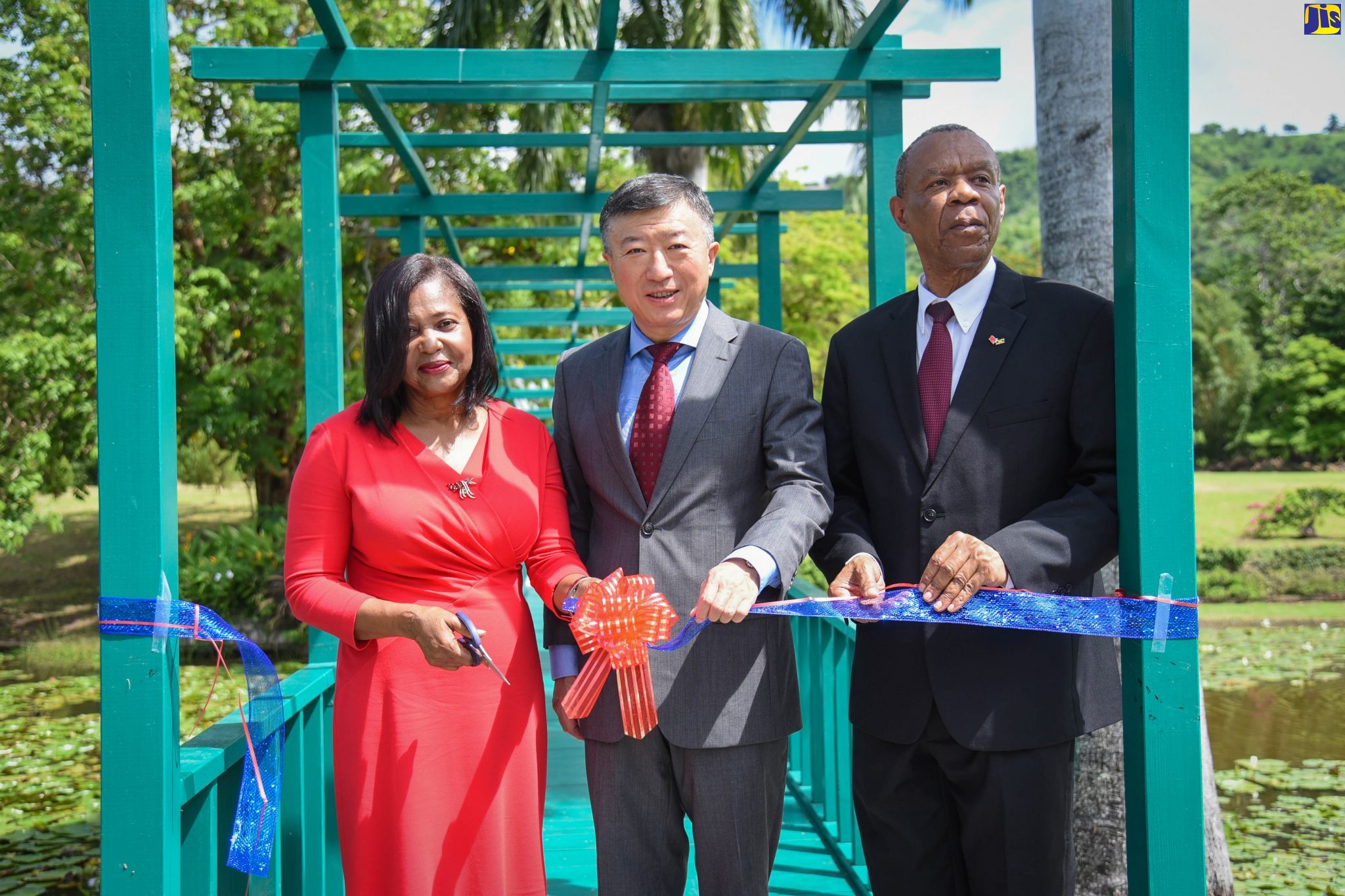 Wife of the Governor-General and Patron of the Hope Royal Botanical Gardens, Her Excellency, the Most Hon. Lady Allen, cuts the ribbon to officially hand over the Lily Pond Bridge at the Chinese Garden on Thursday (October 3). Assisting her are China’s’ Ambassador to Jamaica, His Excellency Tian Qi (centre), and Board Chairman of the Nature Preservation Foundation (NPF), which manages Hope Gardens, Alfred Thomas.
