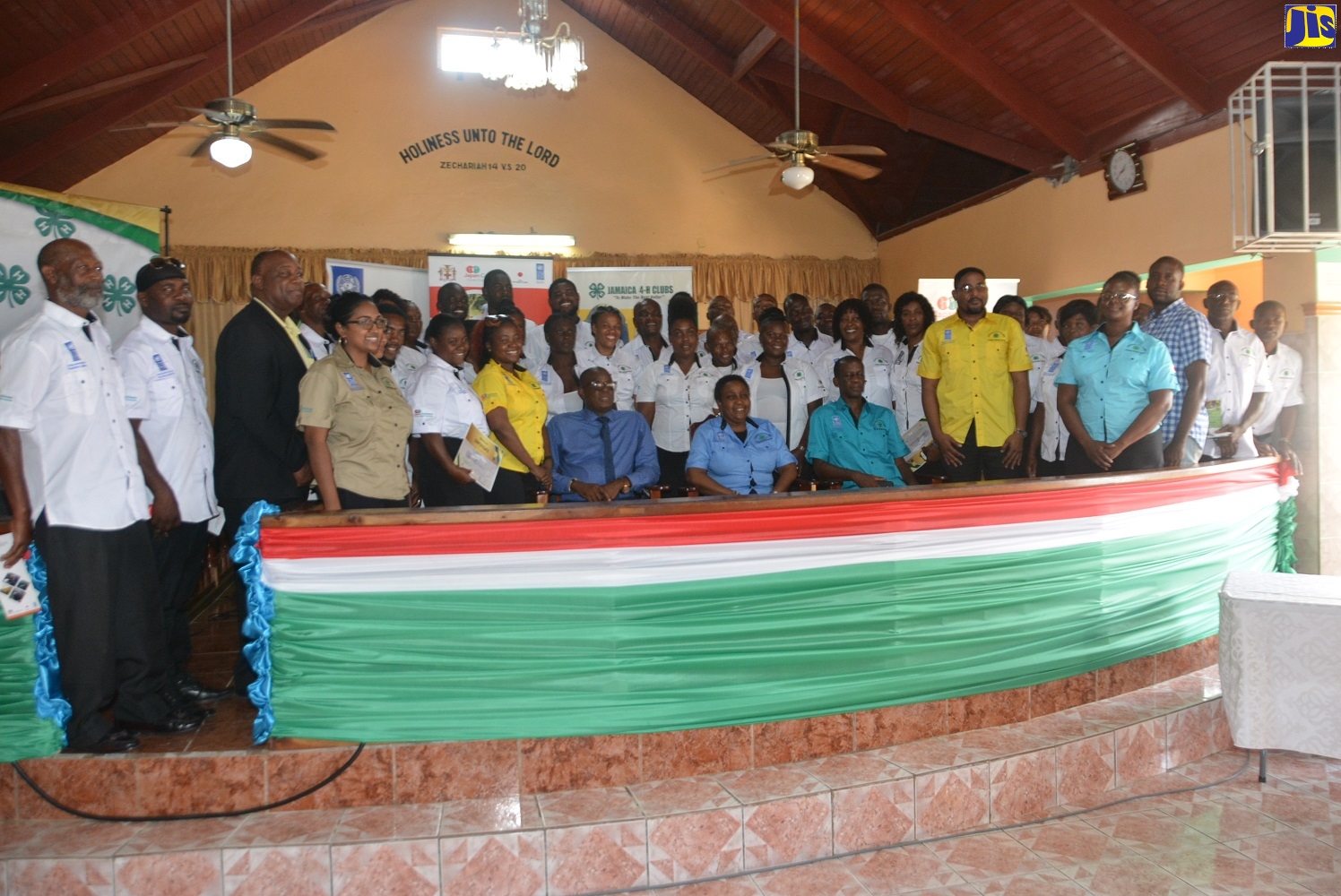 Chief Technical Director at the Ministry of Industry, Commerce, Agriculture and Fisheries (MICAF), Dr. Roy McNeil (seated, left); Japan Caribbean Climate Change Partnership (JCCCP) National Focal Point, UNDP Jamaica, Eltha Brown (centre, seated); and Director of Field Services at the Jamaica 4-H Clubs, Garfield Ewart (third left, seated), with farmers of Cascade in St. Ann, at the closing-out ceremony for a  JCCCP Pilot Project, at the Frazer Church of God of Prophecy in Cascade on Tuesday, October 15.