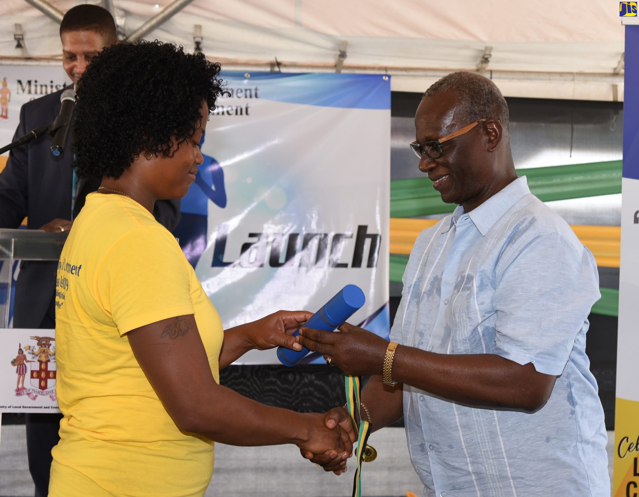 Local Government and Community Development Minister, Hon. Desmond McKenzie (right), presents the Prime Minister’s Message to participant in the Local Government and Community Month 2019 Cross- Island Run, Kelly Ann Fraser. The occasion was the launch of the event on Thursday (October 17) at the Rudolph Elder Park in Morant Bay, St. Thomas.