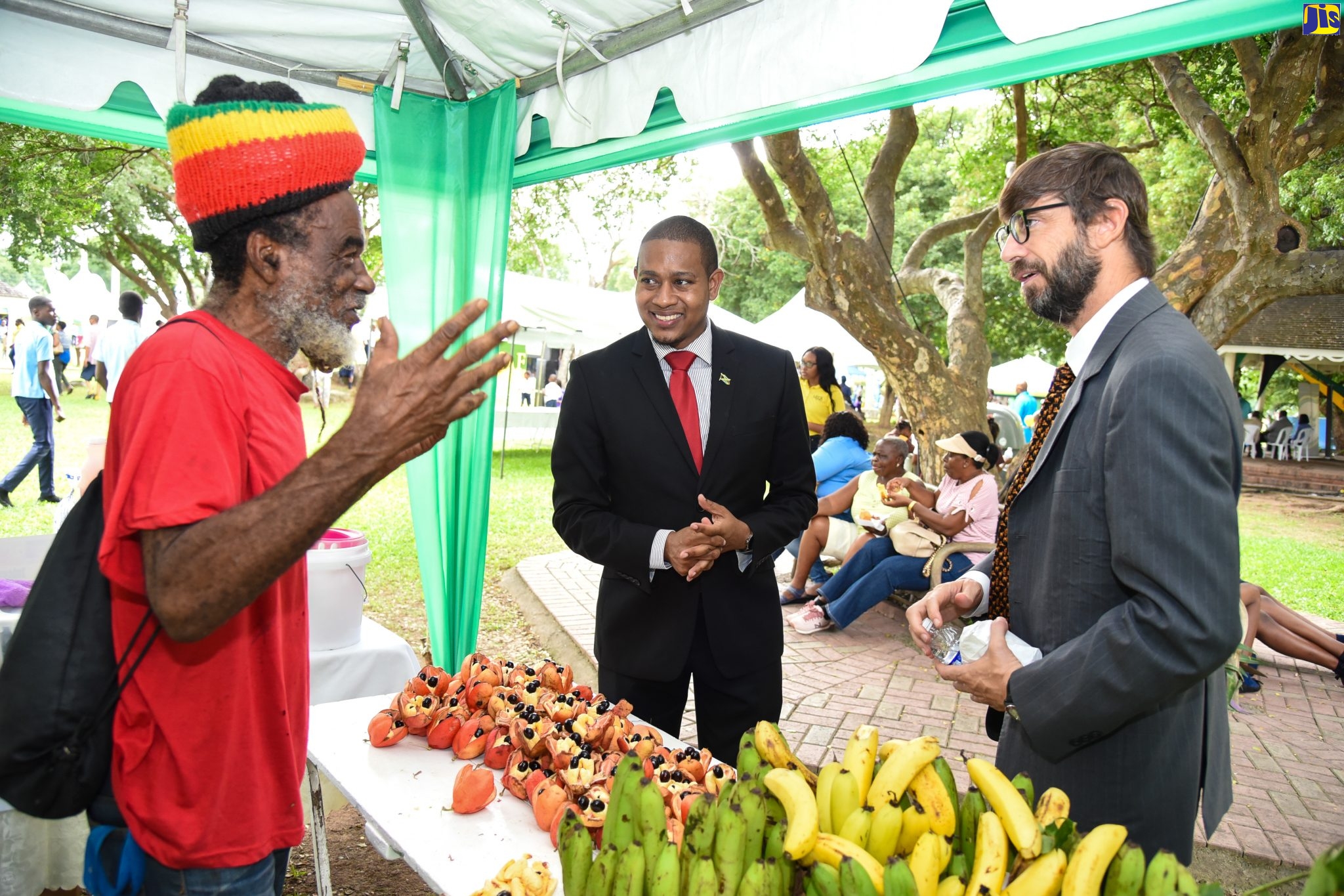 Minister of State in the Ministry of Industry, Commerce, Agriculture and Fisheries, Hon. Floyd Green (centre); and Ambassador of Argentina to Jamaica, His Excellency Luis Del Solar (right), engage with Cedric Hussey of the Mount Charles branch of the Jamaica Agricultural Society (JAS), at the Eat Jamaican Day exposition on the lawns of Devon House in St. Andrew on November 25.