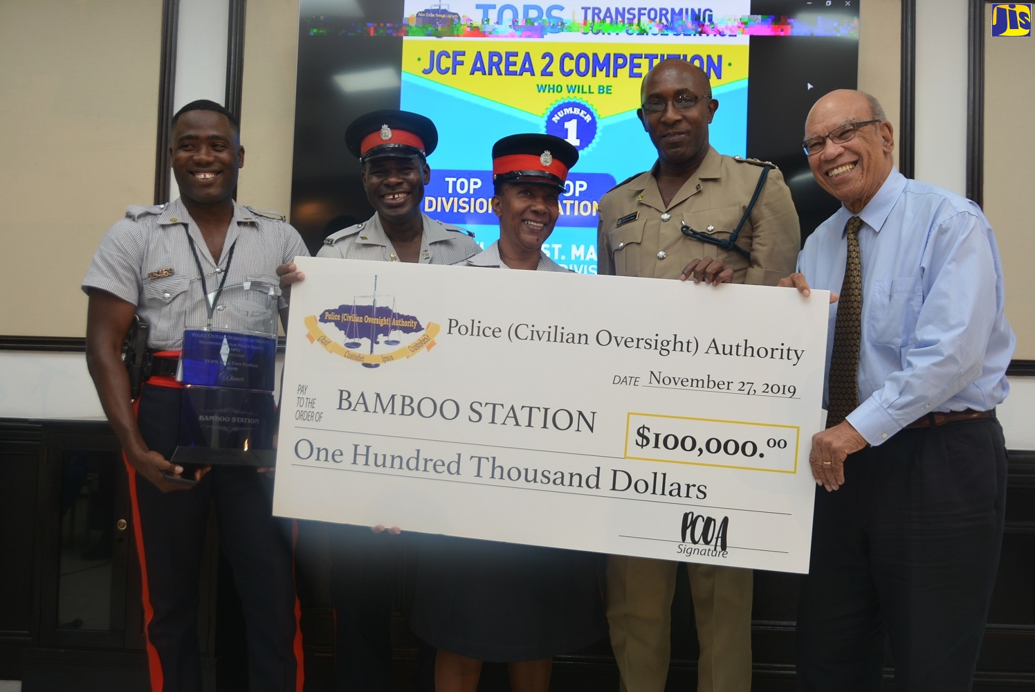 Executive Member of the Police (Civilian Oversight) Authority (PCOA), Marshall Hall (right), presents the ‘Transforming Our Police Service’ (TOPS) Competition first-place cheque to police members of the Bamboo Police Station in St. Ann, during the awards ceremony, held at the Couples San Souci in St. Ann on Wednesday, November 27.  The members are (from left) Constable Rohan Smith, Corporal Ronald Brown, Sergeant Patricia Brown and Commander in charge of the St. Ann Police Division, Senior Superintendent Calvin Small.