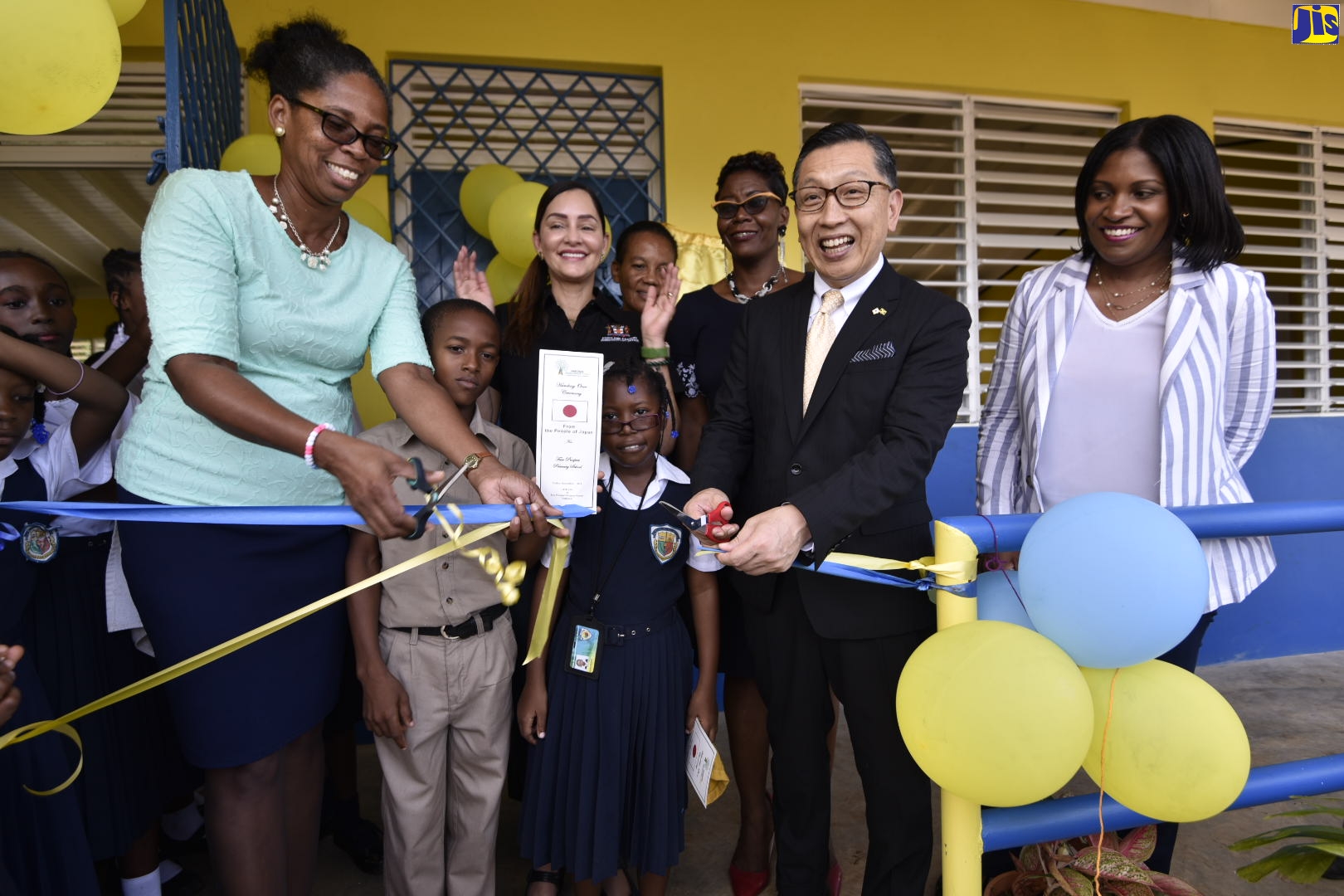 Ambassador of Japan in Jamaica, His Excellency  Hiromasa Yamazaki (second right) and Acting Principal, Fair Prospect Primary School, Ms. Avril Neufville (left), cut the  ribbon to officially open the new classroom block at the school on Friday (November 1). Sharing the moment are Director, Donor and Partner Relations, National Education Trust, Ms. Latoya Harris (right); Member of Parliament for East Portland, Ann Marie Vaz (background, left); Director, Region 2, Ministry of Education, Youth and Information, Ms. Janet Brimm and students of the school.