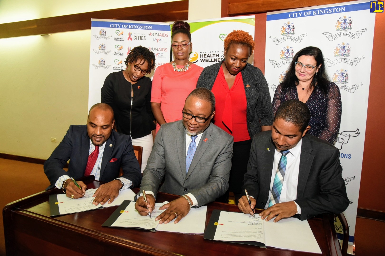 Mayor of Kingston, His Worship, Senator Councillor, Delroy Williams (seated right), signs Memorandum of Understanding with (from left) Chief Executive Officer, Kingston and St. Andrew Municipal Corporation (KSAMC), Robert Hill; and Permanent Secretary, Ministry of Health and Wellness, Dunstan Bryan, at the launch of the Fast-Track Cities Programme on Monday (November 25), at the Jamaica Conference Centre in downtown Kingston. Observing (from left) are Coordinator, Disaster Preparedness/Project Liaison, KSAMC, Terry Forrester; Director, Health Promotion and Protection, Ministry of Health and Wellness, Dr. Simone Spence; Senior Medical Officer, Ministry of Health and Wellness, Dr. Nicole Skyers; and Country Director, UNAIDS, Manoela Manova.
