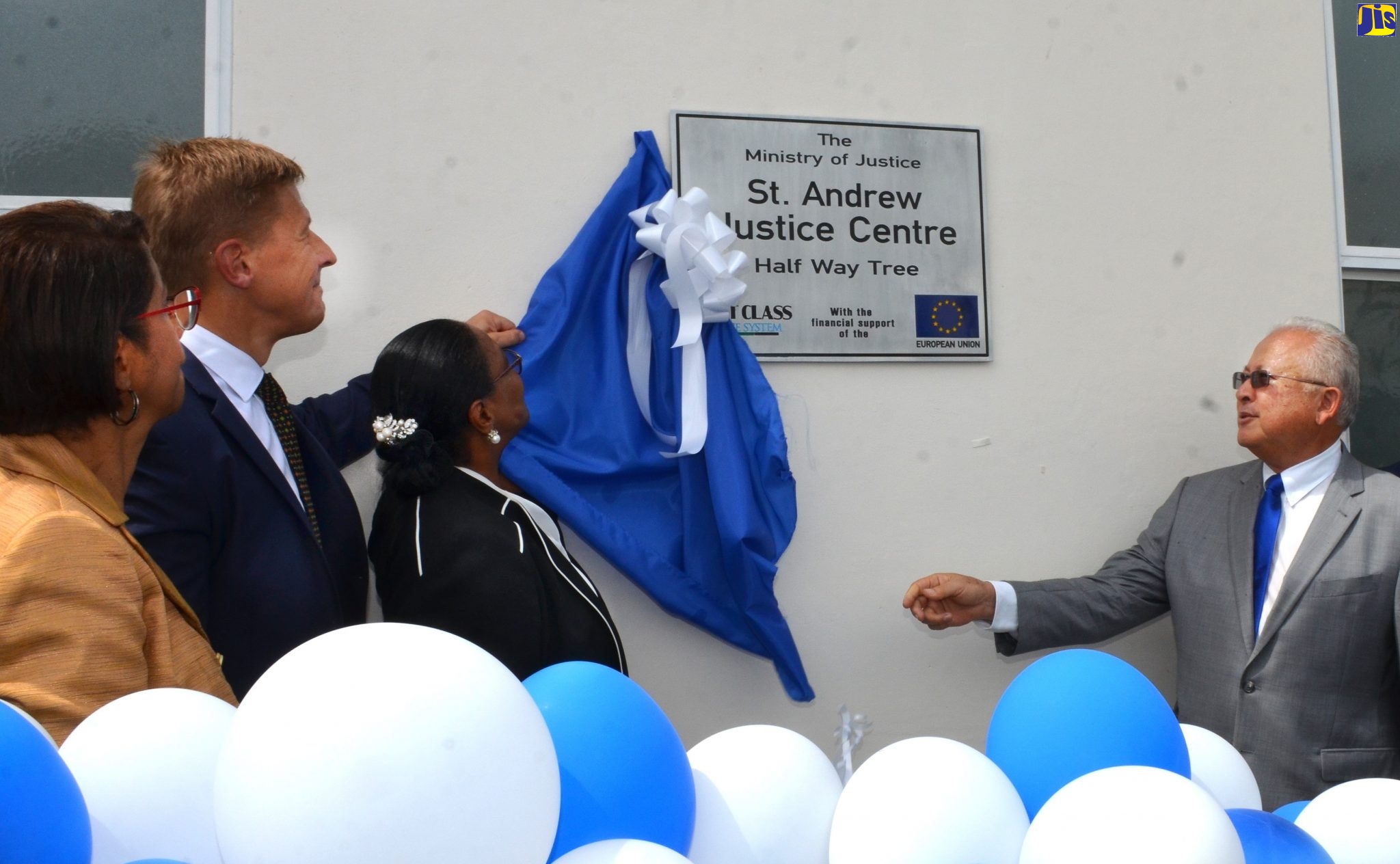Justice Minister, Hon. Delroy Chuck (right), is assisted by Custos Rotulorum of St. Andrew,  Hon. Dr. Patricia Dunwell (third left) and Minister Counsellor/Deputy Head of Mission, European Union (EU) Delegation to Jamaica, Fredrik Ekfeldt (second left), to open the St. Andrew Justice Centre,  Friday (November 1).  At left is  Permanent Secretary in the Ministry of Justice, Sancia Bennett Templer.