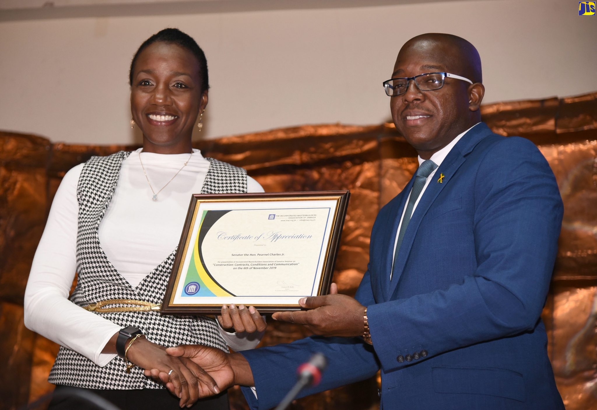 Minister without Portfolio in the Ministry of Economic, Growth and Job Creation, Senator the Hon. Pearnel Charles Jr., receives a certificate of appreciation from Second Vice President, Incorporated Masterbuilders Association of Jamaica (IMAJ), Dahlia Alert, at the IMAJ