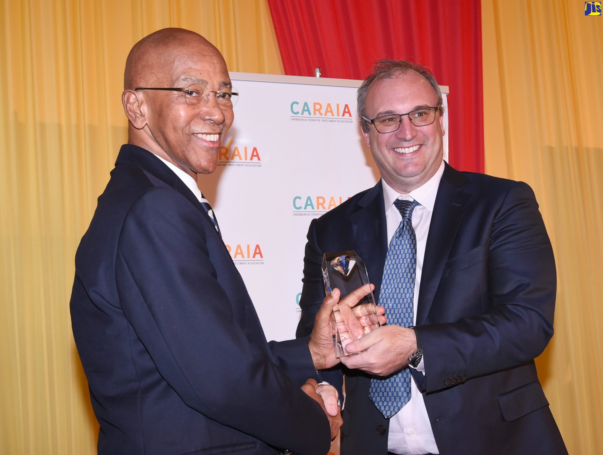 Managing Director, Development Bank of Jamaica (DBJ), Milverton Reynolds (left) accepts a plaque from DBJ Chairman, Paul B. Scott, during the official launch of the Caribbean Alternative Investment Association (CARAIA) at The Jamaica Pegasus hotel in New Kingston on November 15.