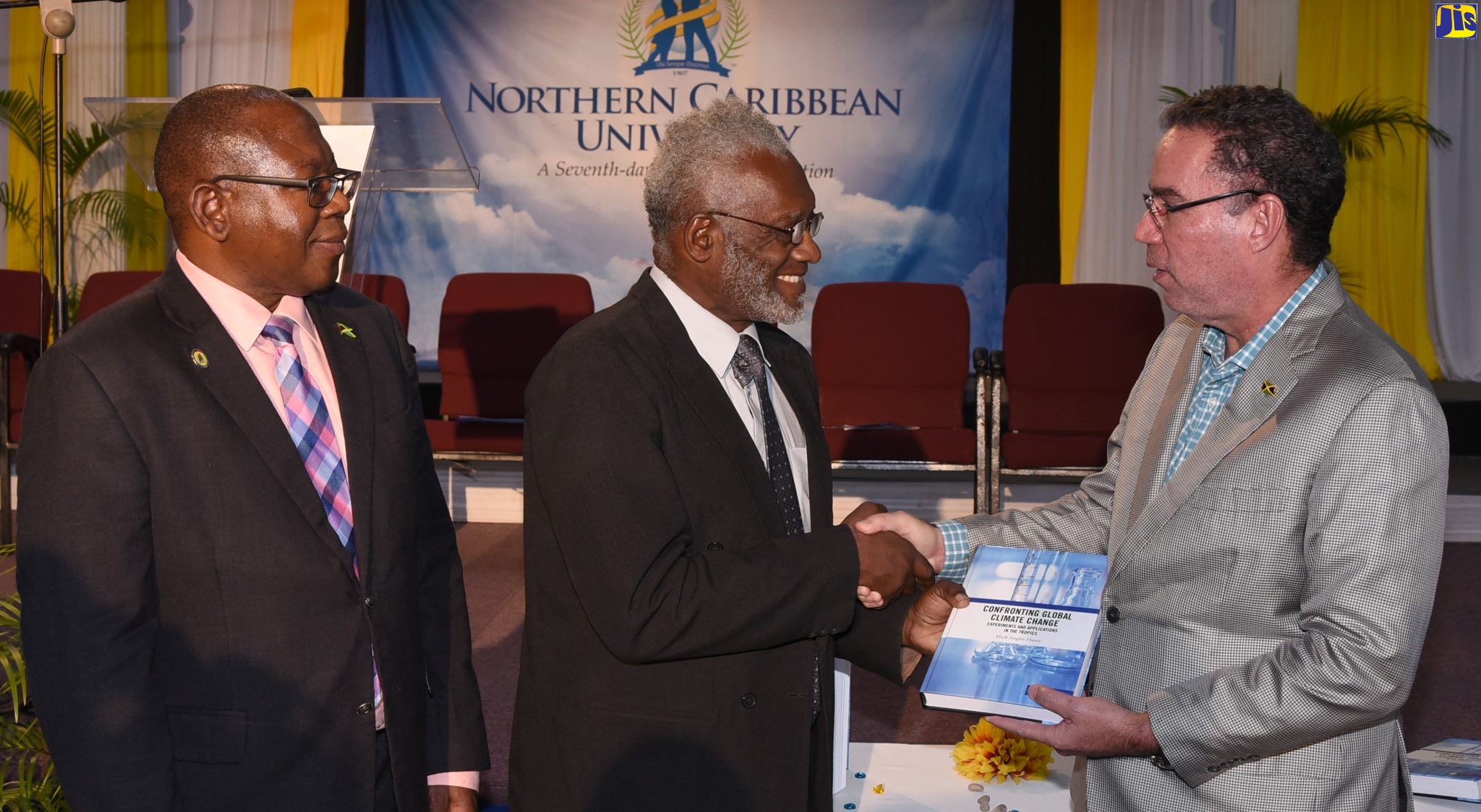 Professor Mark Harris (centre) presents a copy of his book, ‘Confronting Global Climate Change: Experiments and Applications in the Tropics’,  to Minister with responsibility for Land, Environment and  Climate Change,  Hon. Daryl Vaz (right), at the launch, at Northern Caribbean University (NCU), in Mandeville, Manchester, on October 30. At left is President of NCU, Professor Lincoln Edwards.
