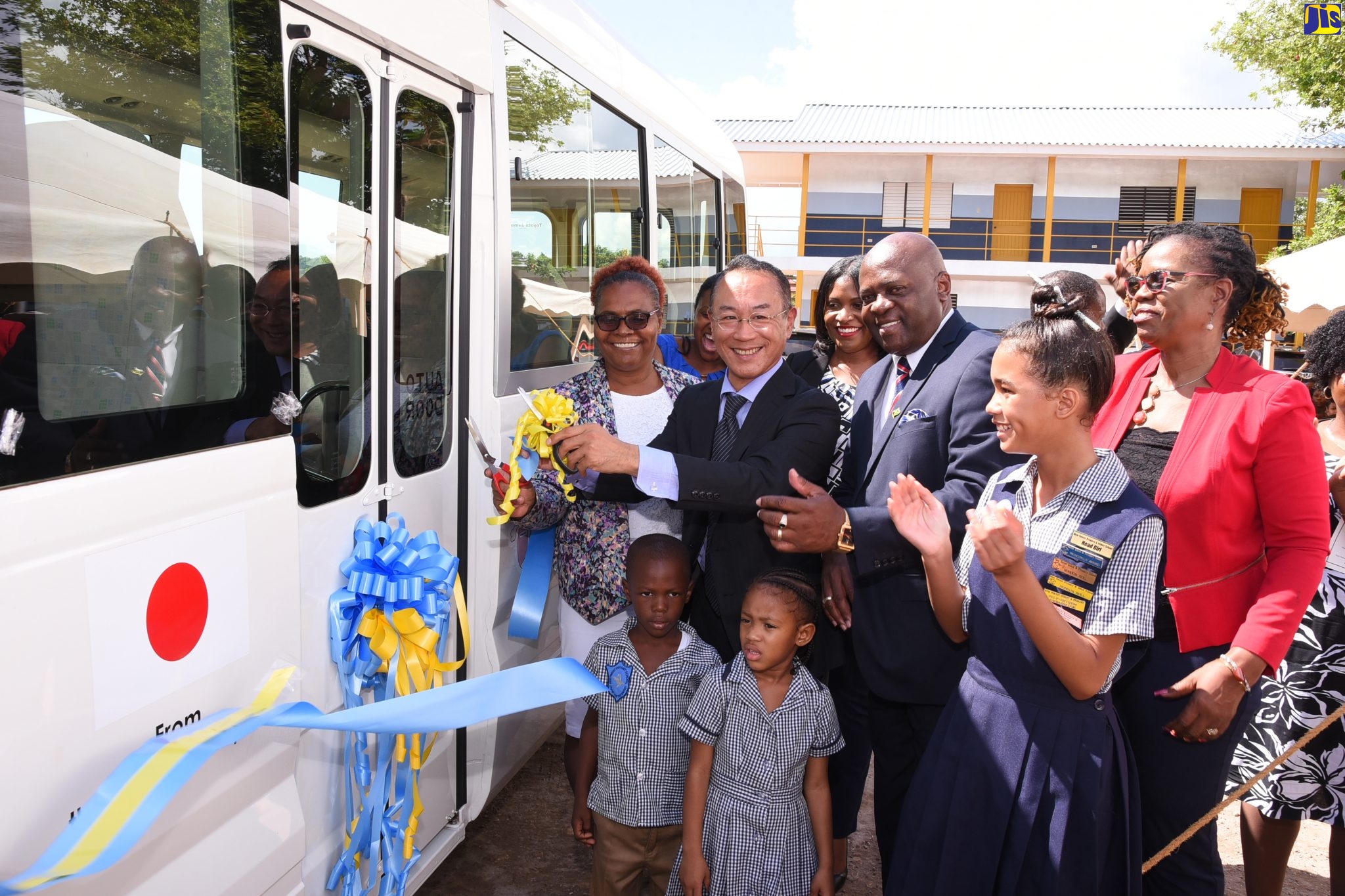 Deputy Head of Mission, Embassy of Japan in Jamaica, Shotoku Habukawa (second left); and Principal of New Forest Infant and Primary School, Sharon Anderson (left), cut the ribbon to officially hand over a school bus, which will support the Expanded Rural School Bus Programme for New Forest Infant and Primary and High schools under the Japan Grassroots Human Security Project. The ceremony was held on the institutions