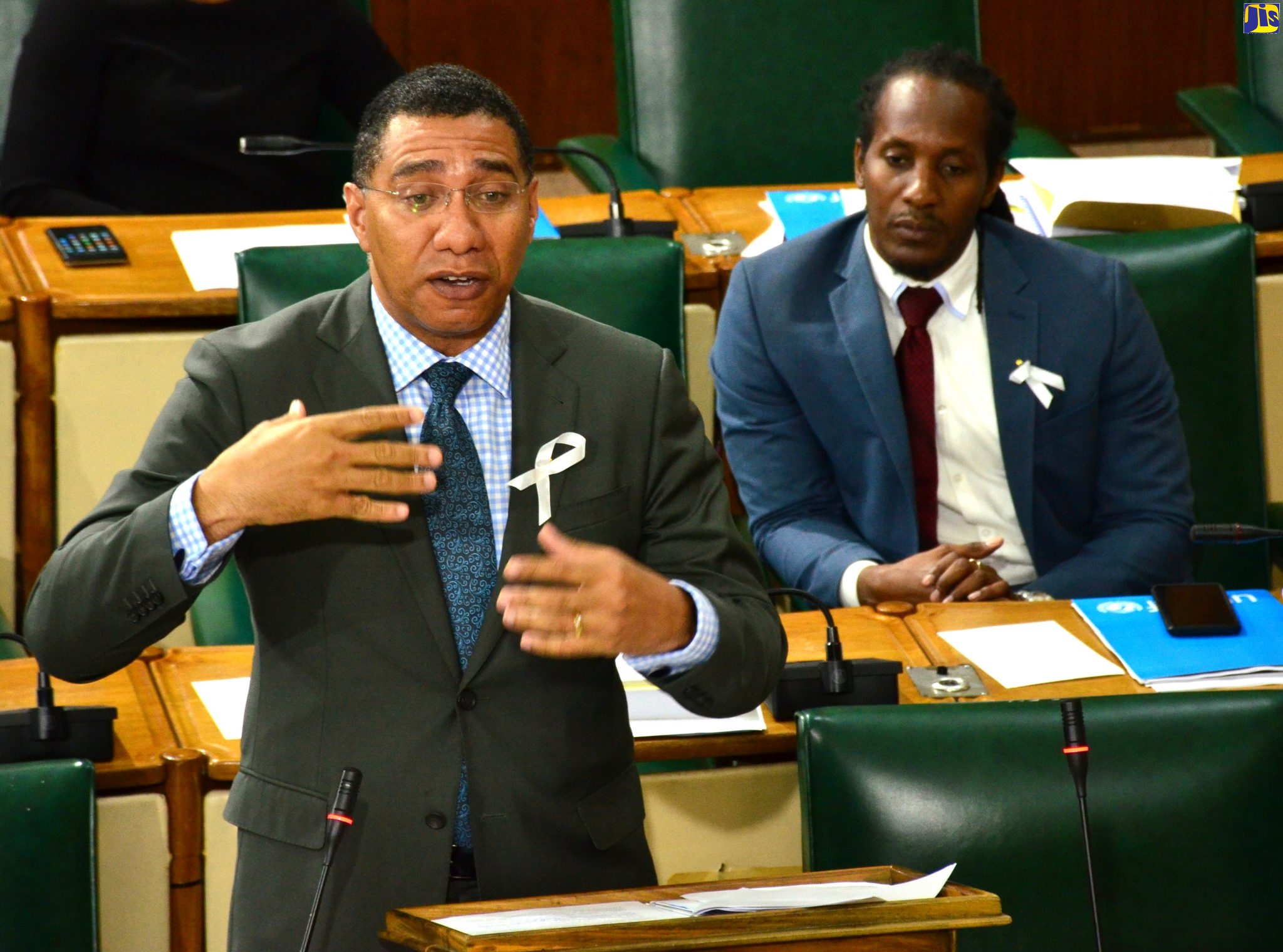 Prime Minister, the Most Hon. Andrew Holness, delivers a statement in the House of Representatives on November 19. Listening (at right) is State Minister in the Ministry of Education, Youth and Information, Hon. Alando Terrelonge.