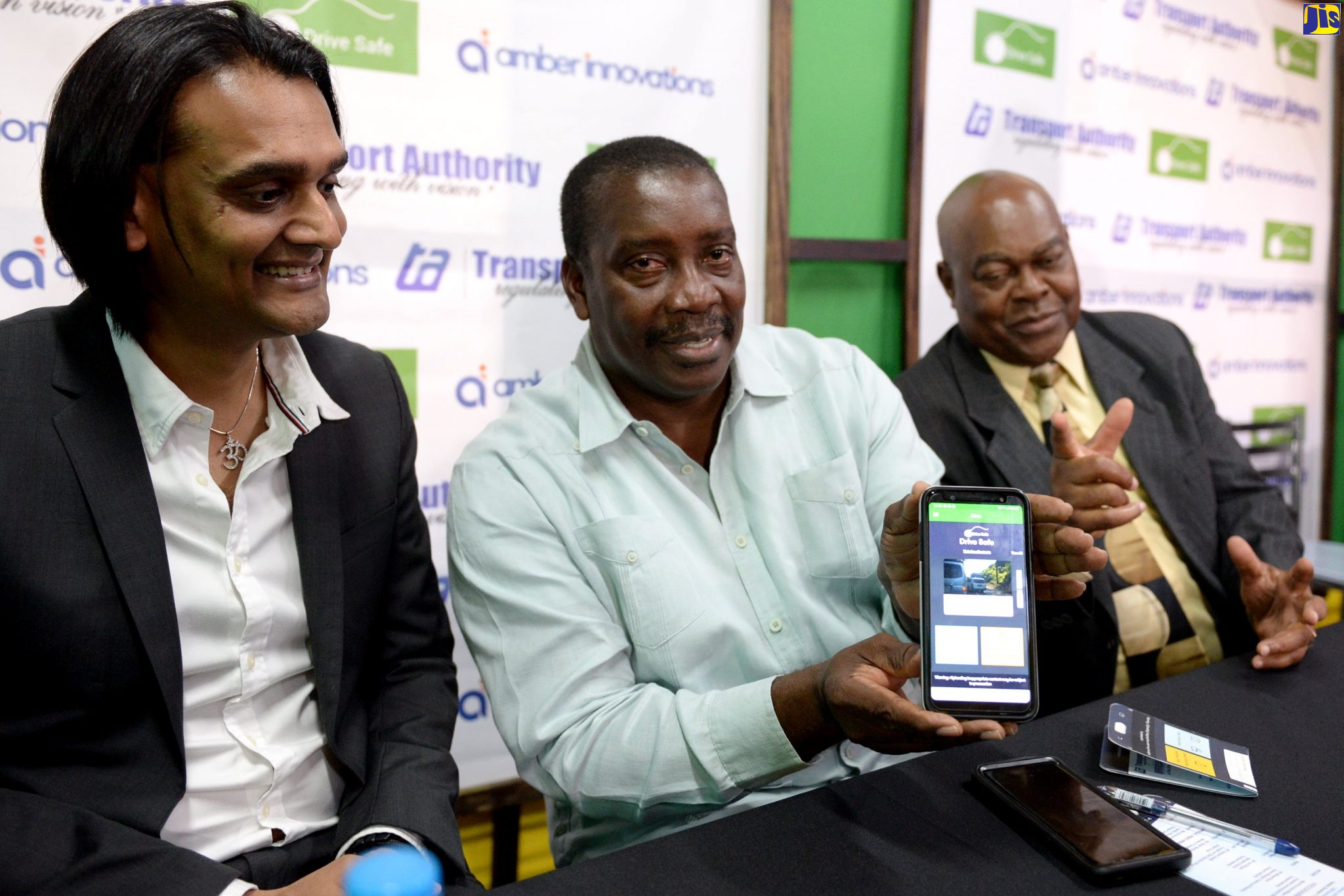 Transport and Mining Minister, Hon. Robert Montague (centre), displays the home screen for the recently developed ‘Drive Safe’ app, which was officially launched on Tuesday (December 17), at the Ministry’s Maxfield Avenue offices in St. Andrew. Sharing the moment are Founder and Chief Executive Officer of the Amber Group, Dushyant Savadia (left); and Managing Director of the Transport Authority, Cecil Morgan.