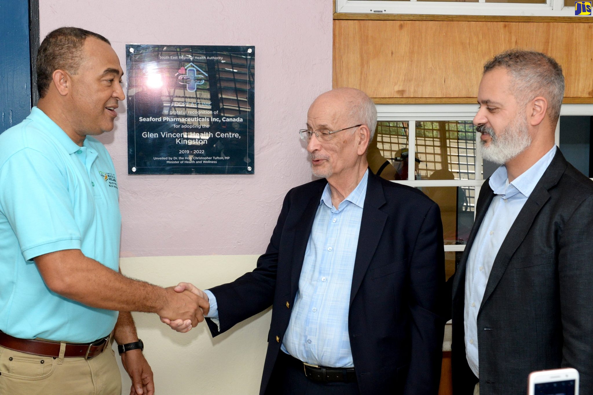 Health and Wellness Minister, Dr. the Hon. Christopher Tufton (left), shakes the hand of Founder and Chief Executive Officer of Seaford Pharmaceuticals Inc, Ron Seales (centre), at the official ceremony for the adoption of the Glen Vincent Health Centre by Seaford Pharmaceuticals, held on Wednesday (Deember.11), at the facility