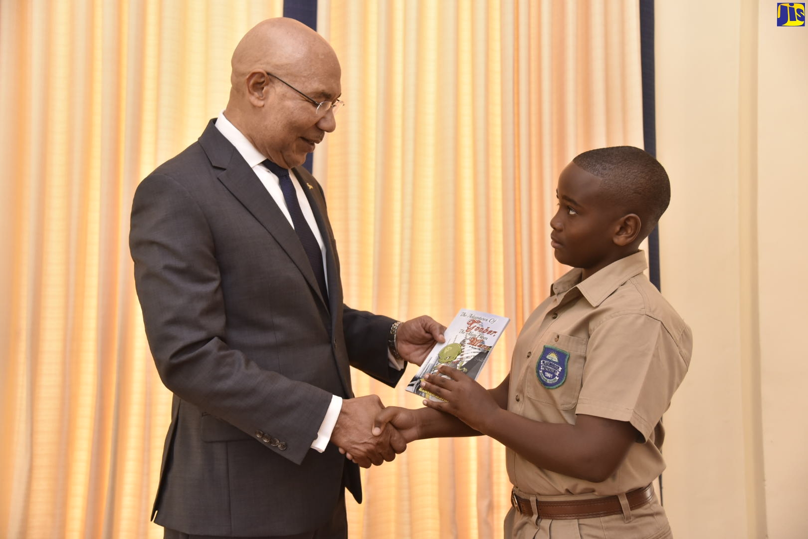 Governor-General, His Excellency the Most Hon. Sir Patrick Allen (left), is presented with a copy of the book ‘The Adventures Of Goober, The Alien From Mars’, by the author, 10-year-old Kanton Hardy, at King’s House, on December 6.
