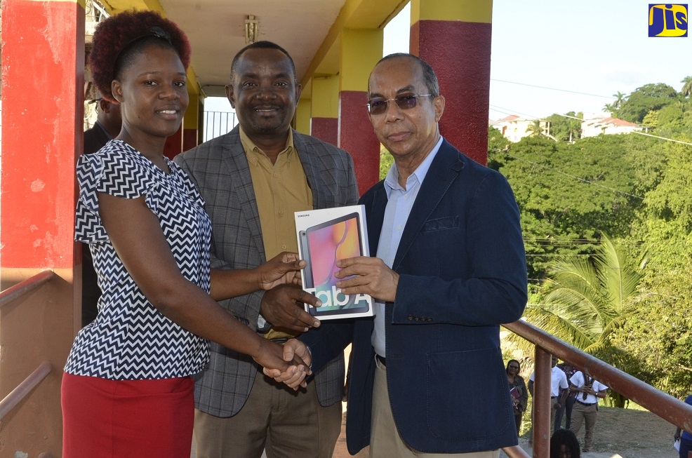 Minister of National Security, Hon. Dr. Horace Chang (right) presents a tablet computer to Principal of Cornwall College, Michael Ellis (centre) and Acting Head of the Information Technology and Business Department at the school, Audia Cole on the grounds of the institution in Montego Bay, St. James on November 29.