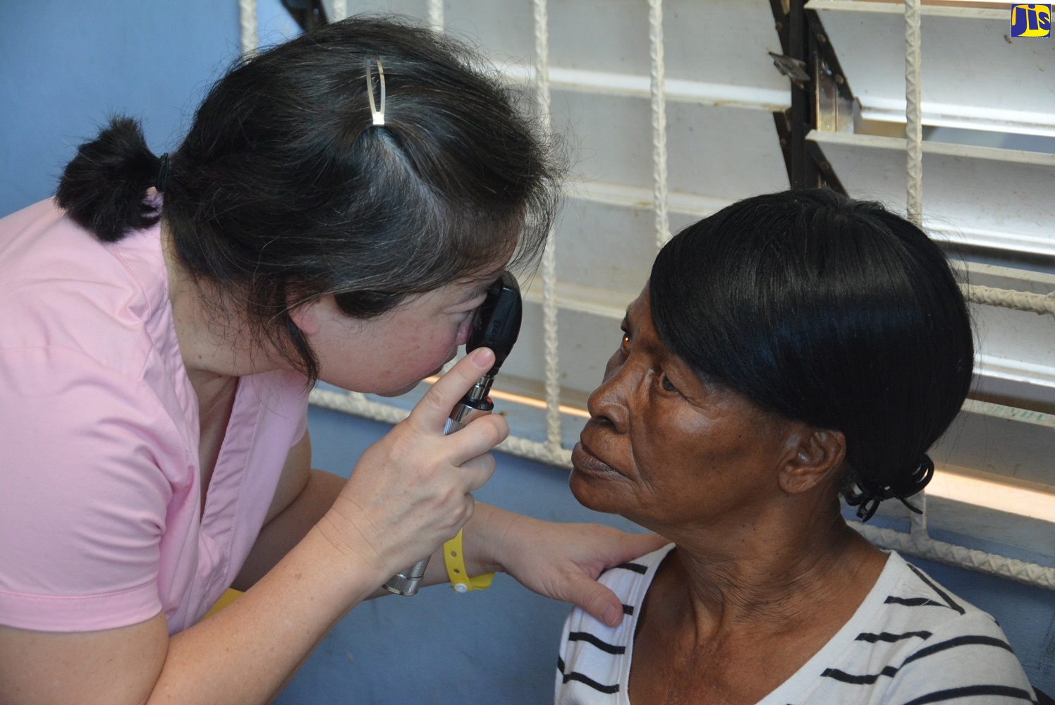 Optometrist, Stephanie Yee (left), examines the eyes of patient, Daphne Bernard, at the Don Daly Medical Mission in Flanker, St. James, on Tuesday (December 10). Simultaneous clinics were held in Negril and Ketto in Westmoreland.