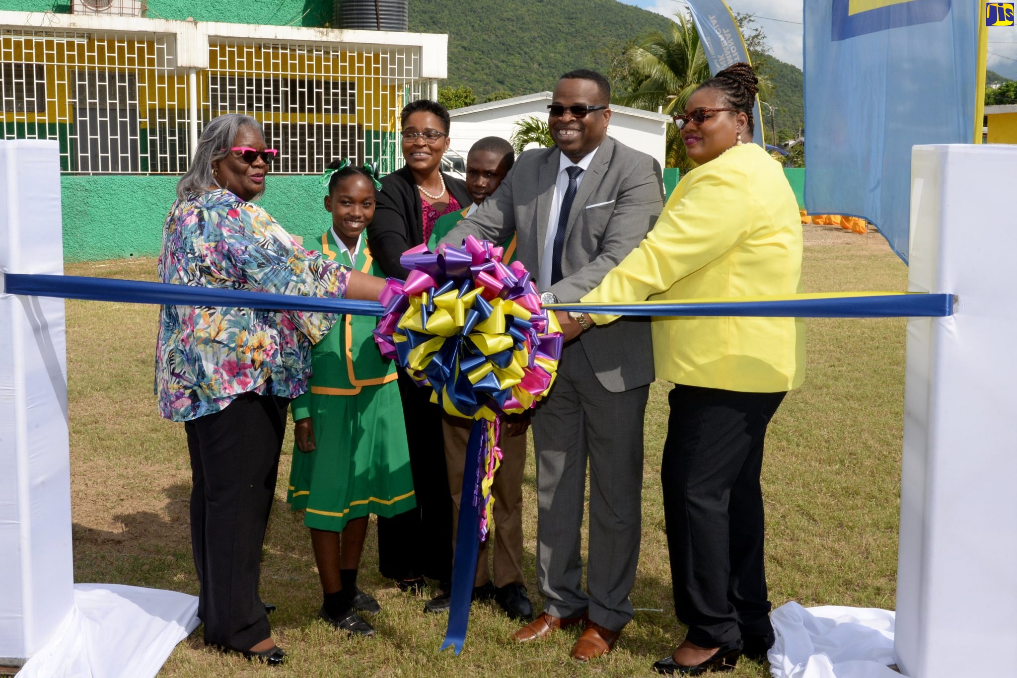 Principal of Duhaney Park Primary School, Coleen Reid Grant (right), cuts the ribbon to officially open the renovated playing field at the school in St. Andrew on Thursday (December 5).  She is joined by (from left) Vice President at Guardian Group, Claudette Ashman; Headgirl, Amoya Edwards; Marketing Projects Officer, National Commercial Bank (NCB), Gillian Parague; Headboy, Rojay Peaches; and School Board Chairman, Rev. Christopher Hutchinson.