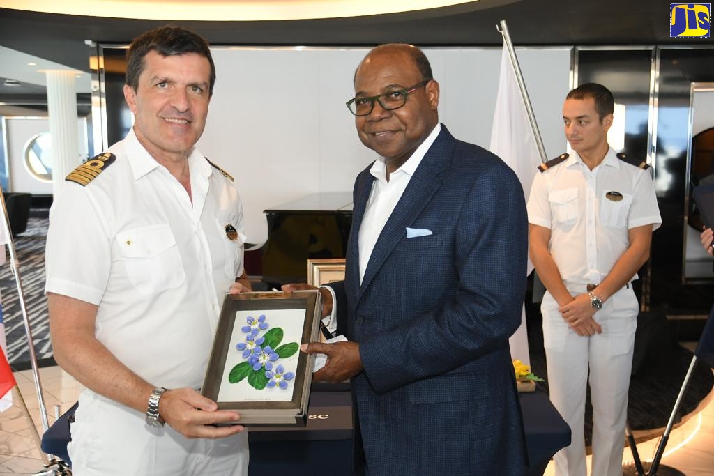 Tourism Minister, Hon. Edmund Bartlett (right) gives Captain of the MSC Meraviglia, Stephano Battinelli,  an authentic Jamaican gift at the official welcome reception for the cruise ship’s inaugural visit to Ocho Rios on December 3. In the background is Hotel Manager of the MSC Meraviglia, Antonio Castellana. Minister Bartlett announced that the MSC Meraviglia will bring 50,000 cruise passengers between now and April of next year.