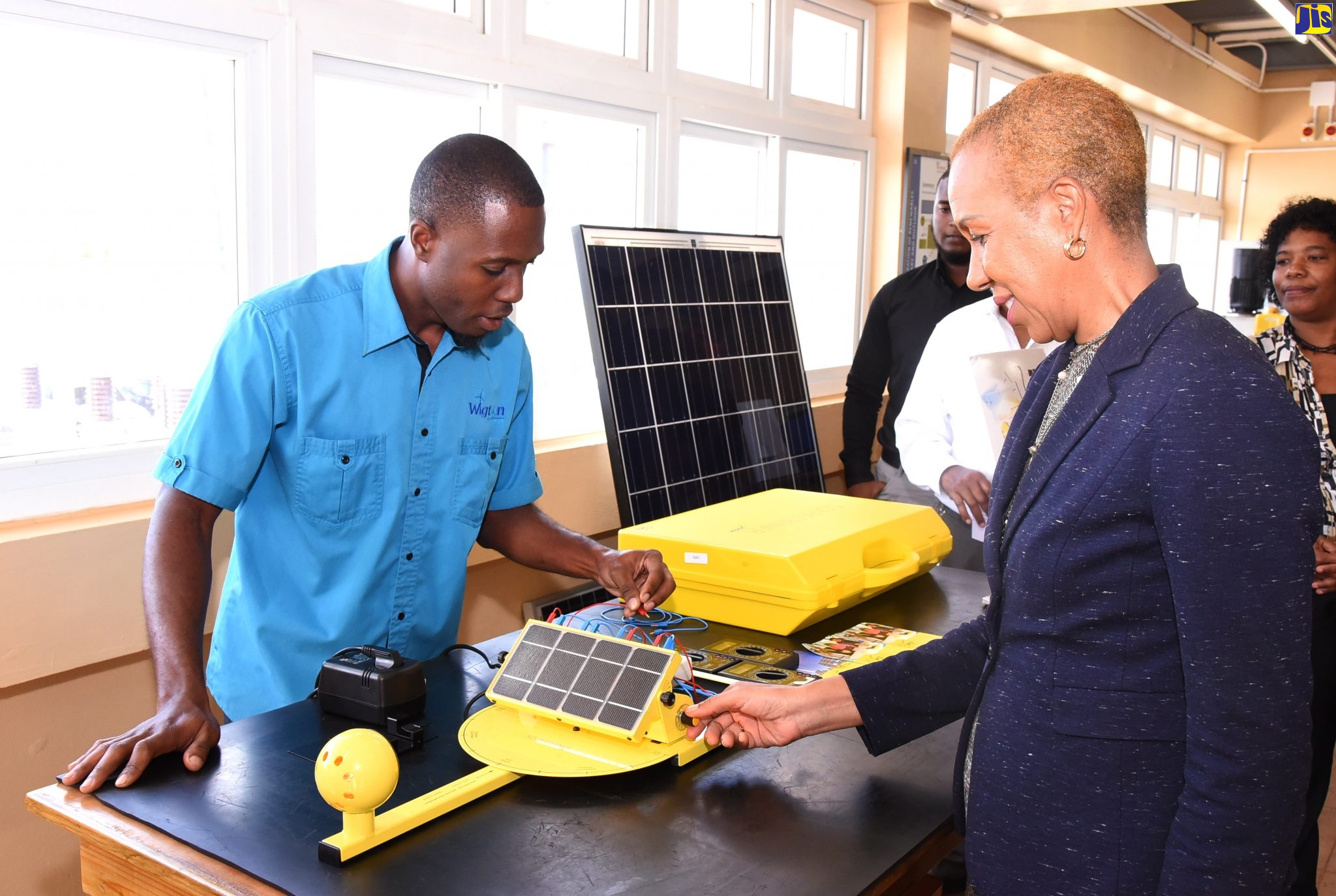 Minister of Science, Energy and Technology, Hon. Fayval Williams (right), turns the knob on a piece of equipment used in generating solar energy, under the guidance of Service Engineer at Wigton Wind Farm, Joel Lewinson. Occasion was a tour of the wind farm in Rose Hill, Manchester, on December 13.