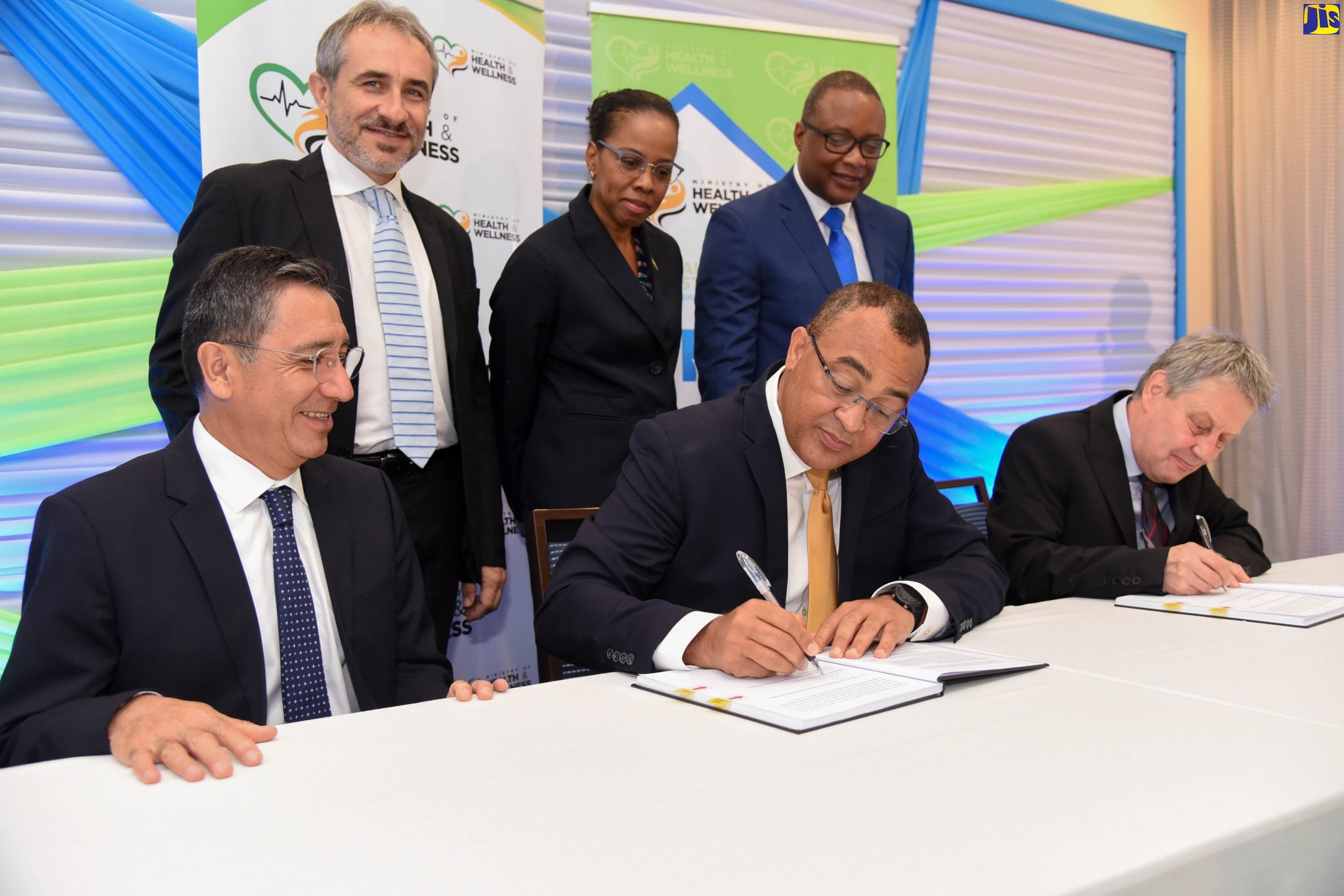 Minister of Health and Wellness, Dr. the Hon. Christopher (seated, centre), signs a contract valued at US$674,000 with Director, Project Planning and Management Limited, Borislav Stoyanov (seated right), to provide designs for the upgrade of 13 health facilities over the next 11 months under the Health Systems Strengthening Programm’. The signing ceremony took place at the Courtyard by Marriott in New Kingston on January 28, where the programme was officially launched. Others (from left) are Inter-American Development Bank (IDB) Team Lead for the Health Systems Strengthening Programme, Ricardo Perez-Cuevas; Attaché Cooperation Section, European Union Delegation to Jamaica, Gabrio Marinozzi; Acting Chief Medical Officer, Ministry of Health and Wellness, Dr. Karen Webster Kerr; and Permanent Secretary in the Ministry, Dunstan Bryan.