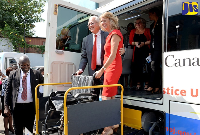 Justice Minister, Hon. Delroy Chuck (left, foreground), and Canada’s High Commissioner to Jamaica, Her Excellency Laurie Peters, display a wheelchair on the ramp of one of two newly acquired retrofitted mobile justice units, which were handed over during a ceremony in the Ministry’s car park on Constant Spring Road in Kingston on Wednesday (January 29). The units, valued at Can$420,000, were provided by the Government of Canada through the Justice Undertakings for Social Transformation (JUST) programme.