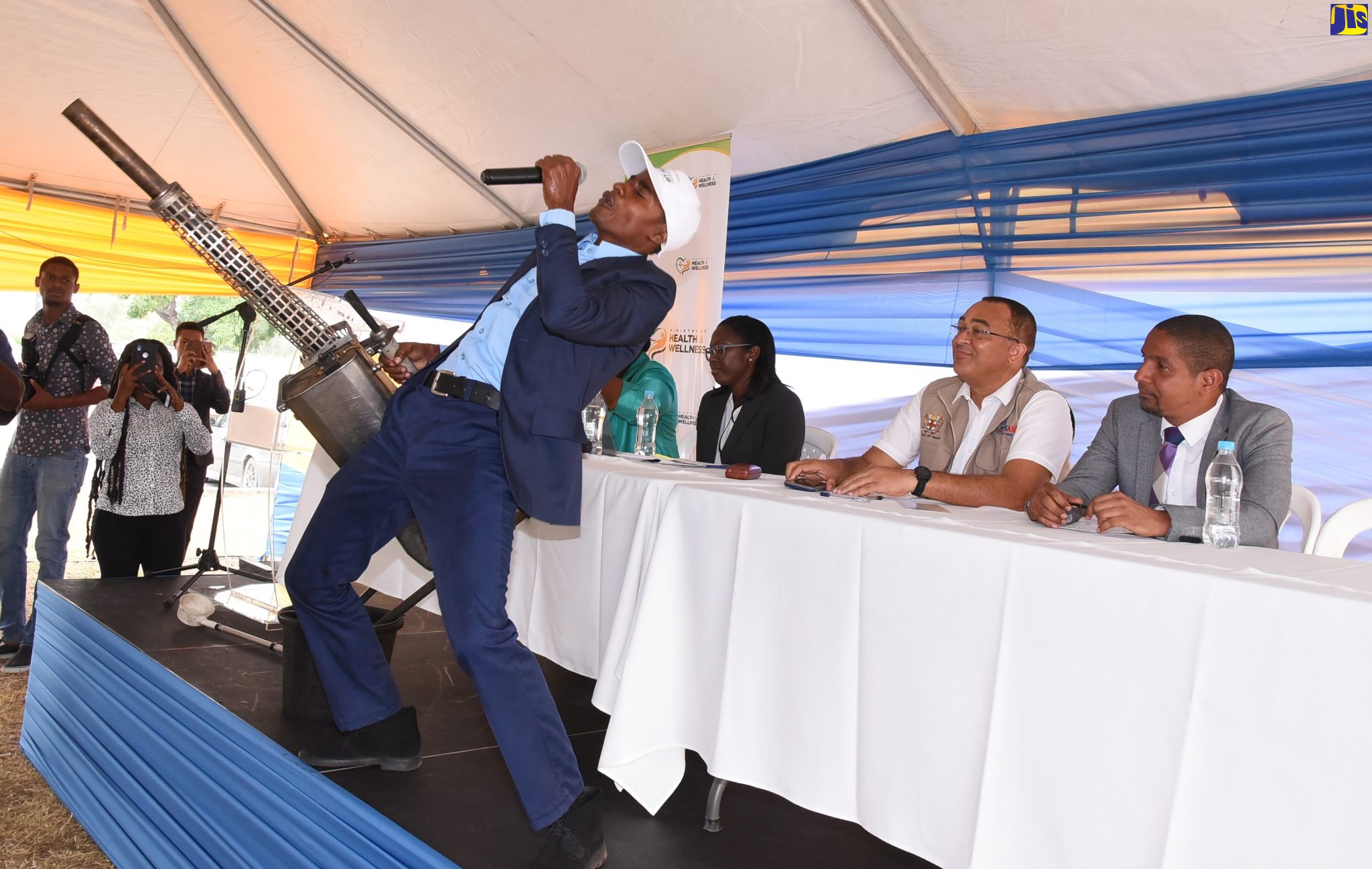 Minister of Health and Wellness, Dr. the Hon. Christopher Tufton (second right); and Mayor of Kingston, Senator Councillor Delroy Williams, observe as vector-control worker, Kingston and St. Andrew Health Department, Troy Fletcher (foreground), performs an item describing the methods used to eradicate mosquitoes, during the handover of 50 new vector-control vehicles at the Ranny Williams Entertainment Centre on January 27. To Dr. Tufton’s right is Medical Officer of Health, Kingston and St. Andrew Health Department, Dr. Kimberly Myers.