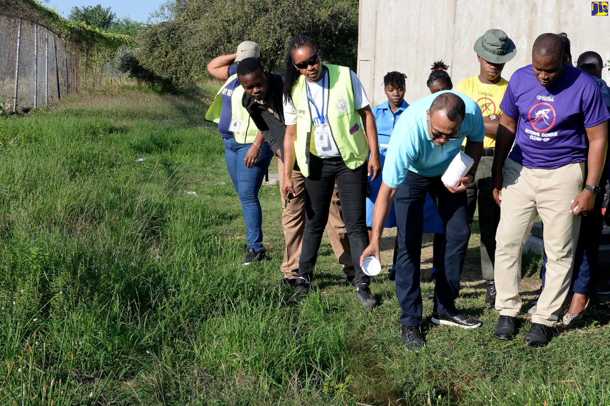 Minister of Health and Wellness, Dr. the Hon. Christopher Tufton (second right), applies larvicide to a small pool of water on the grounds of the St. Catherine High School on Friday (January 24) as part of the National Dengue Clean-up exercise. Observing are Principal of the school, Marlon Campbell (right), students, and vector-control workers.