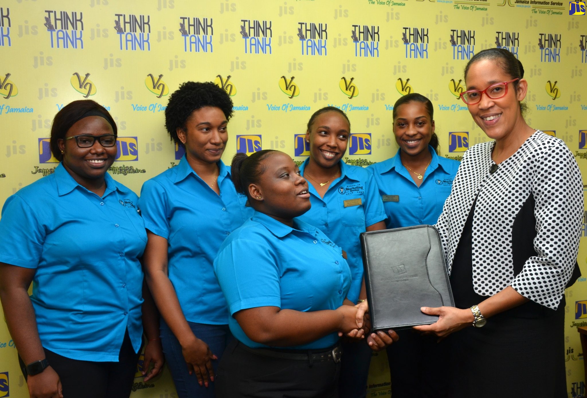 Chief Executive Officer of the Jamaica Information Service (JIS), Donna-Marie Rowe (right), presents University of Technology (UTech) communication student, Amoy Bailey, with a branded JIS folder, after she and her group participated in a recent mini sensitisation session on the role of the Public Relations and Marketing Department of the agency in disseminating information on the Government’s policies and programmes.  Other members are (from left) Shannon Graham, Chelsi McLean, Renae Williams, and Deshauna Wheeler.