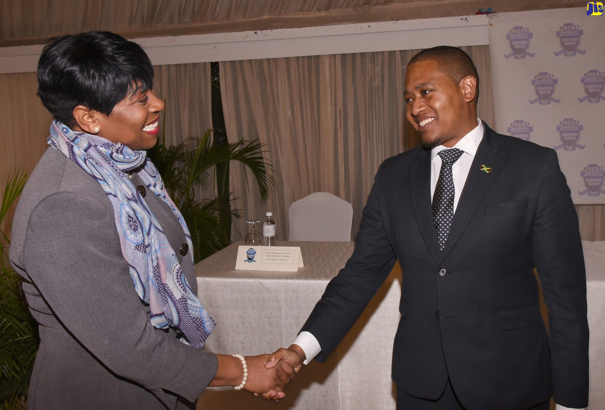 Minister of State in the Ministry of Industry, Commerce, Agriculture and Fisheries, Hon. Floyd Green, greets Head of the Jamaica Constabulary Force (JCF) Corporate Communications Unit, Senior Superintendent of Police, Stephanie Lindsay, at the Jamaica Used Car Dealers Association