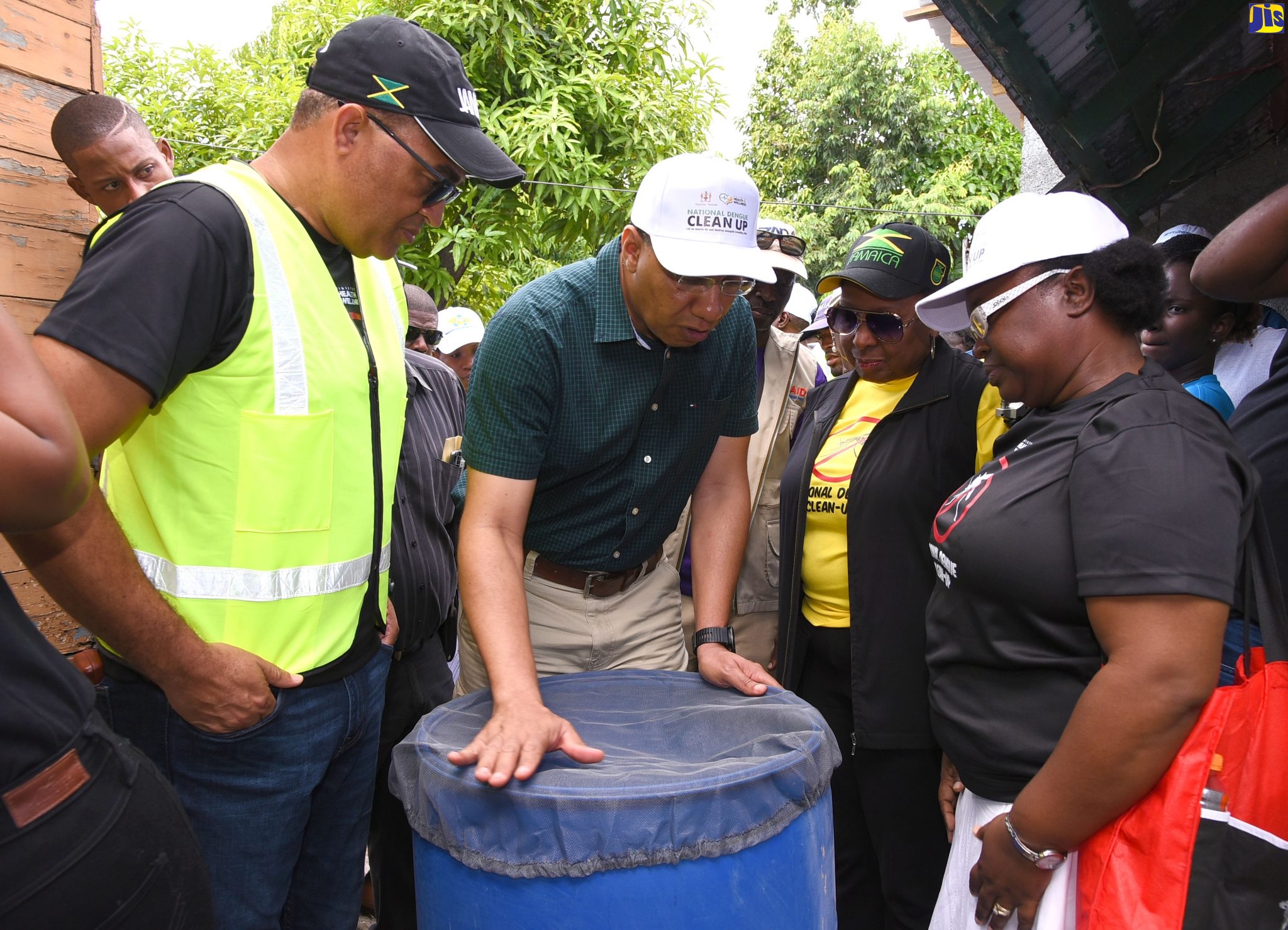 Prime Minister, the Most Hon. Andrew Holness (second left), covers a 45-gallon water drum at a home in Grants Pen, St Andrew, during the national dengue cleanup exercise on January 25. Looking on (from left) are Minister of Health, Dr. the Hon. Christopher Tufton; Minister of Culture, Gender Entertainment and Sport, Hon. Olivia Grange, and Medical Entomologist and Programme Manager for the Vector Control Programme in the Ministry of Health, Sherine Huntley Jones.