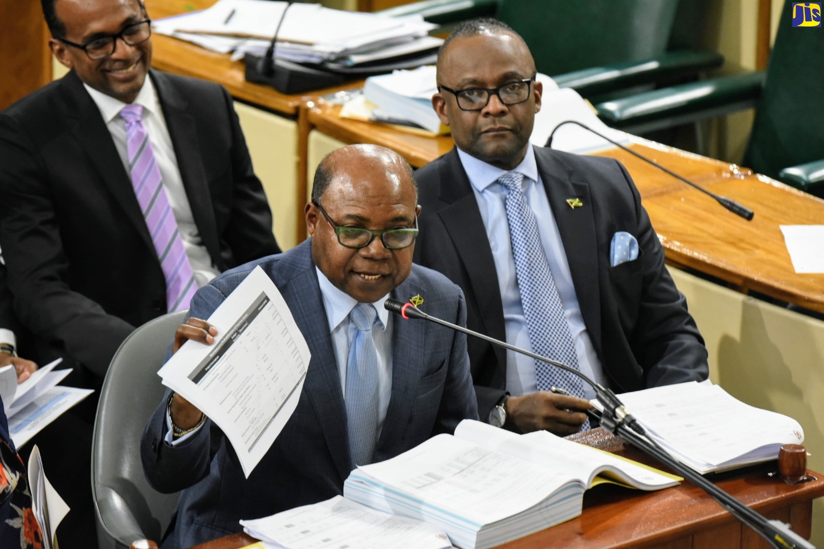 Tourism Minister, Hon. Edmund Bartlett (left), refers to a document while addressing the Standing Finance Committee of the House of Representatives on Tuesday (March 3). Beside him is Tourism Director of Tourism, Donovan White, while in the background is Tourism Enhancement Fund Executive Director, Dr. Carey Wallace.