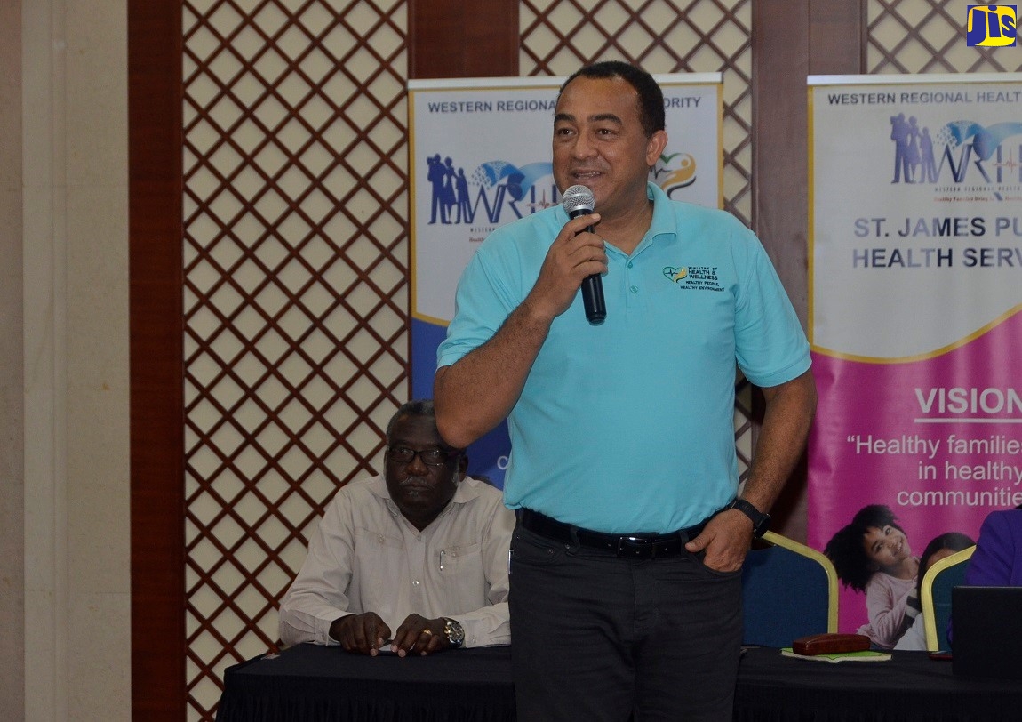 Minister of Health and Wellness, Dr. the Hon. Christopher Tufton  speaking at a meeting with stakeholders in western Jamaica at the Montego Bay Convention Centre, St. James on Friday (March 13). Seated left is Custos Rotulorum for St. James, Bishop, the Hon. Conrad Pitkin.