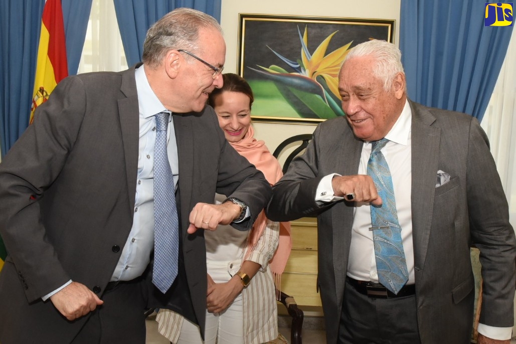 Minister without Portfolio in the Office of the Prime Minister, Hon. Mike Henry (right), exchanges an elbow bump with Ambassador of Spain to Jamaica, His Excellency Josep Maria Bosch (left), during a courtesy call at Jamaica House on March 12. Looking on is Economic and Commercial Counsellor, Embassy of Spain, Clara Fernández Martin.
