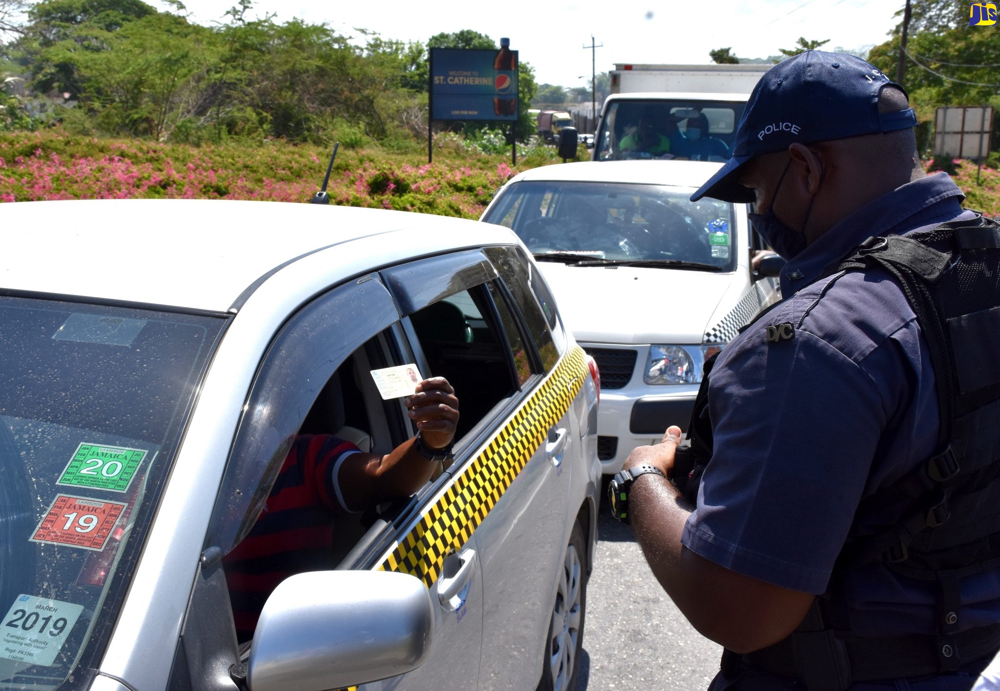 A passenger in a taxi shows his identification to a police officer at a checkpoint at the Clarendon/St. Catherine border on Friday morning (April 17). Various checkpoints have been established throughout St. Catherine, following Prime Minister, the Most Hon. Andrew Holness’ announcement on April 14 of a lockdown of the parish in a bid to contain the spread of the coronavirus (COVID-19). The seven-day lockdown is effective from 5:00 a.m. on Wednesday, April 15 to 5:00 a.m. on Wednesday, April 22, 2020.