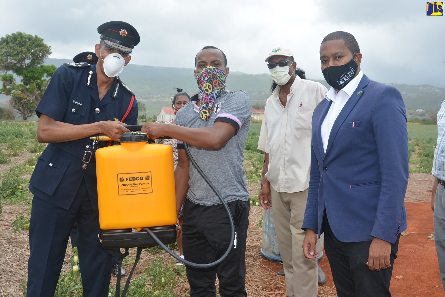 Commissioner of the Jamaica Fire Brigade (JFB), Stewart Beckford (left), hands over one of the two firefighting backpack pumps to Flagaman Farmers
