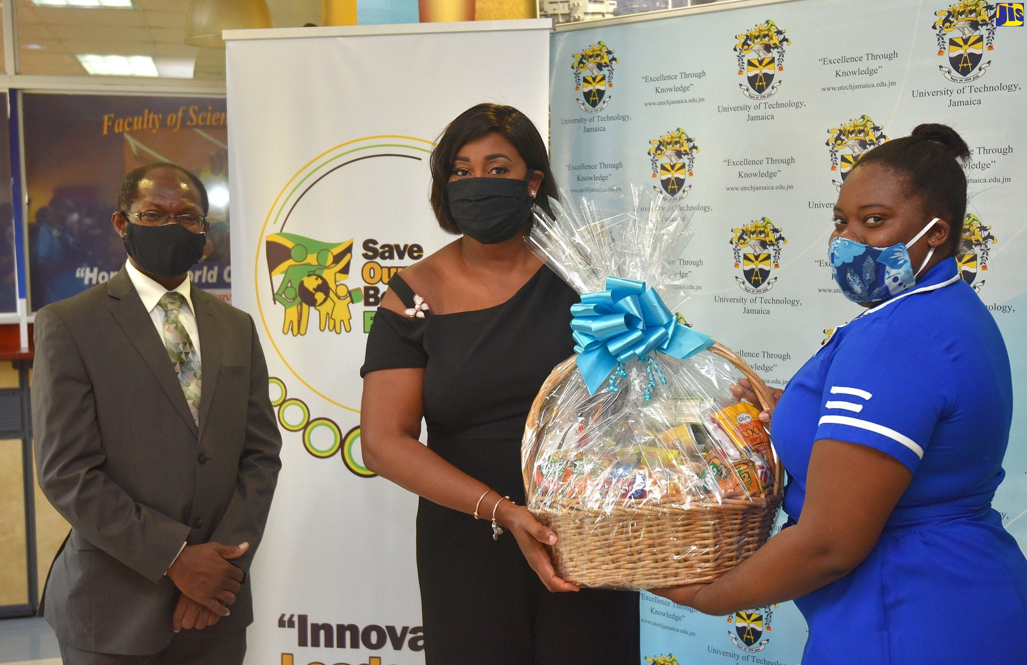 Wife of the Prime Minister and Founder of the Save Our Boys and Girls Foundation, the Most Hon. Juliet Holness (centre) presents a care package to third-year midwifery student at the University of Technology (UTech), Ashleigh Mitchell (right). Looking on is Acting President of UTech, Professor Colin Gyles. Occasion was the presentation of care packages to 53 and midwifery students at UTech