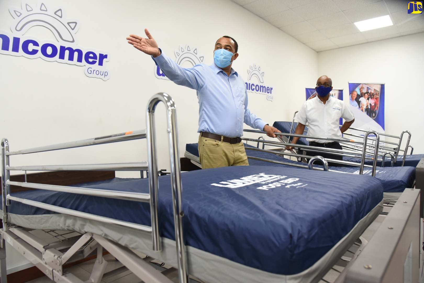 Health and Wellness Minister, Dr. the Hon. Christopher Tufton (left), gestures as he speaks to Managing Director, Unicomer (Courts) Jamaica Limited, Dennis Harris (right), at the official presentation of beds by Courts to the Ministry, on May 8, at the Unicomer Distribution Centre in Kingston.