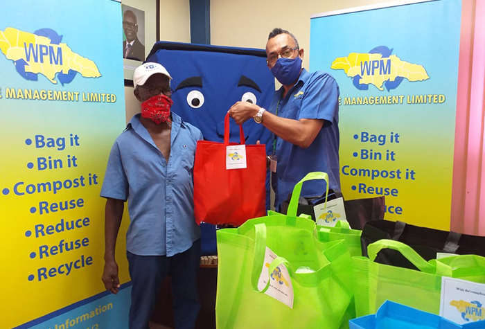 Public Cleansing Manager at the Western Parks and Market (WPM) Waste Management Limited,  Mark Jones (right), hands over a bag of groceries to former WPM employee, Gladstone Miles, during a recent distribution drive to assist retirees impacted by the novel coronavirus (COVID-19).

 
